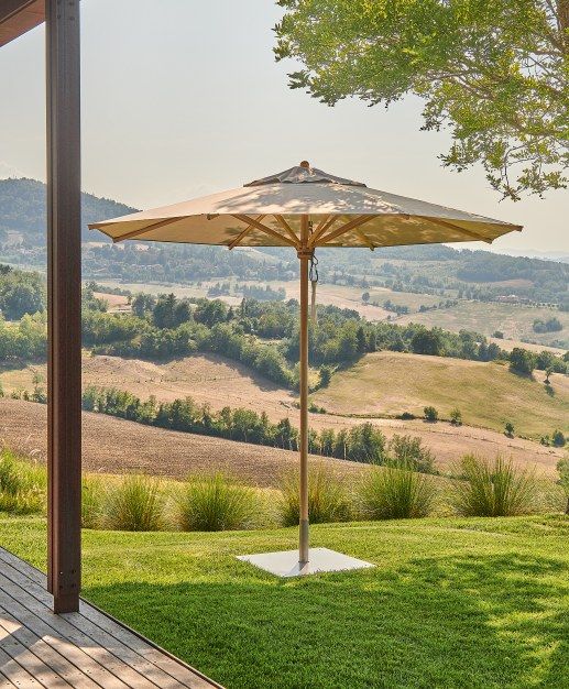 Weishäupl Klassiker Sonnenschirm mit Holzgestell und beigem Schirmstoff im Garten mit Blick auf hügelige Landschaft.