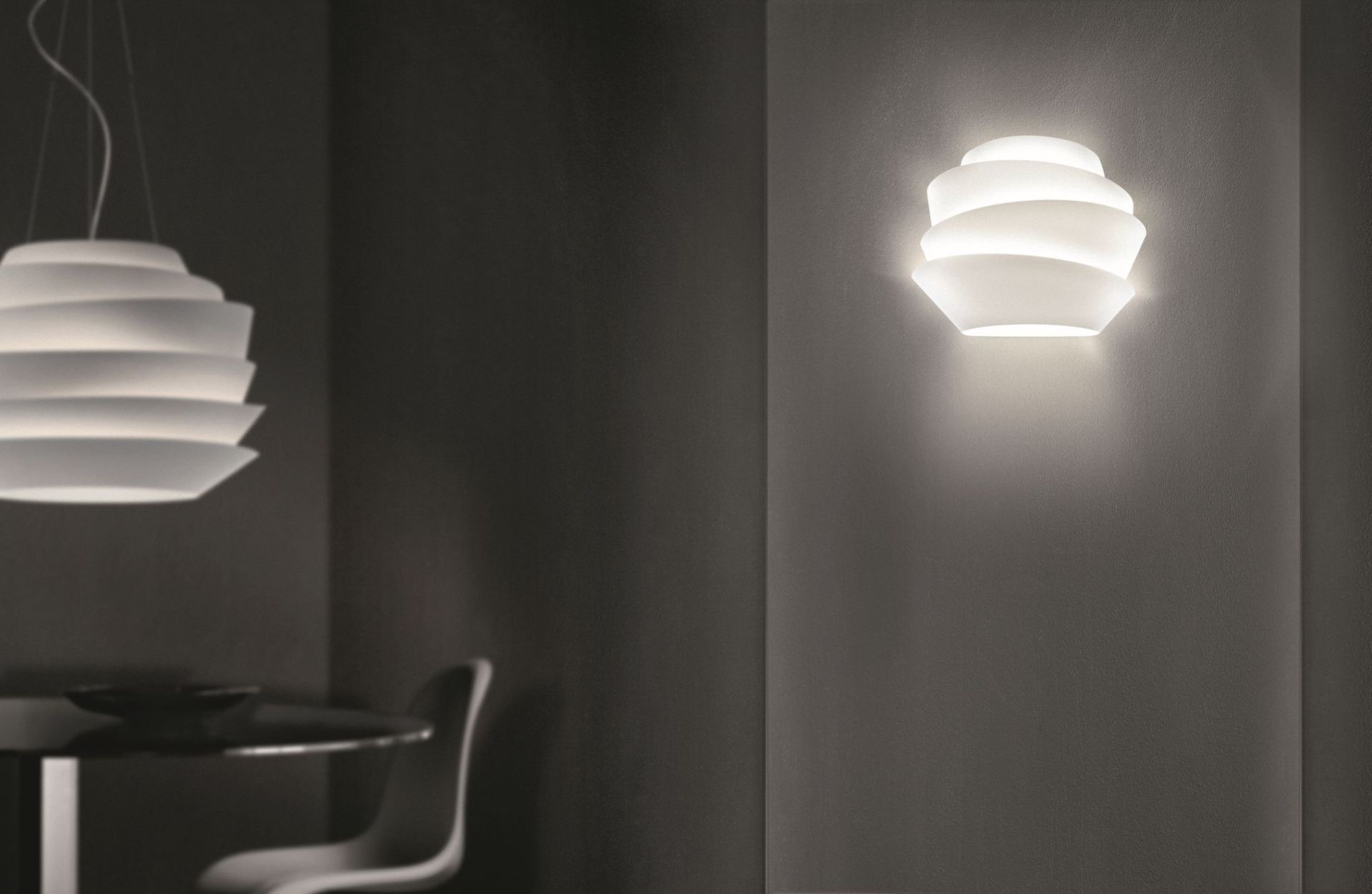 Weiße Le Soleil Wandleuchte von Foscarini an dunkler Wand, indirekte Beleuchtung für modernes Wohnambiente.