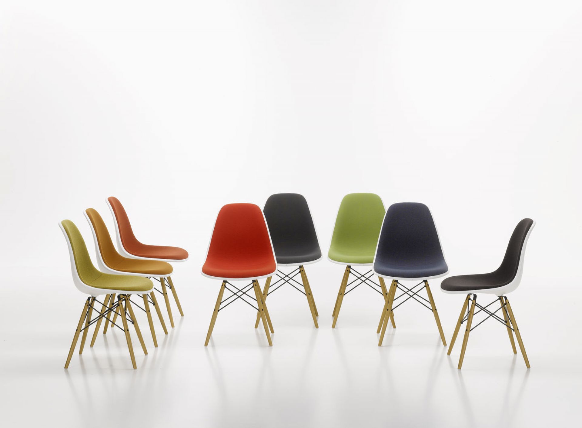 Mehrere Eames Plastic Side Chairs DSW mit Vollpolsterung von Vitra in verschiedenen Farben.