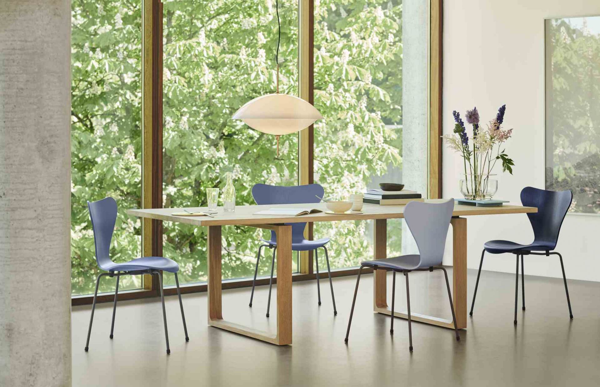 Heller Essay Tisch von Fritz Hansen mit blauen Stühlen und Pendelleuchte in modernem Esszimmer.