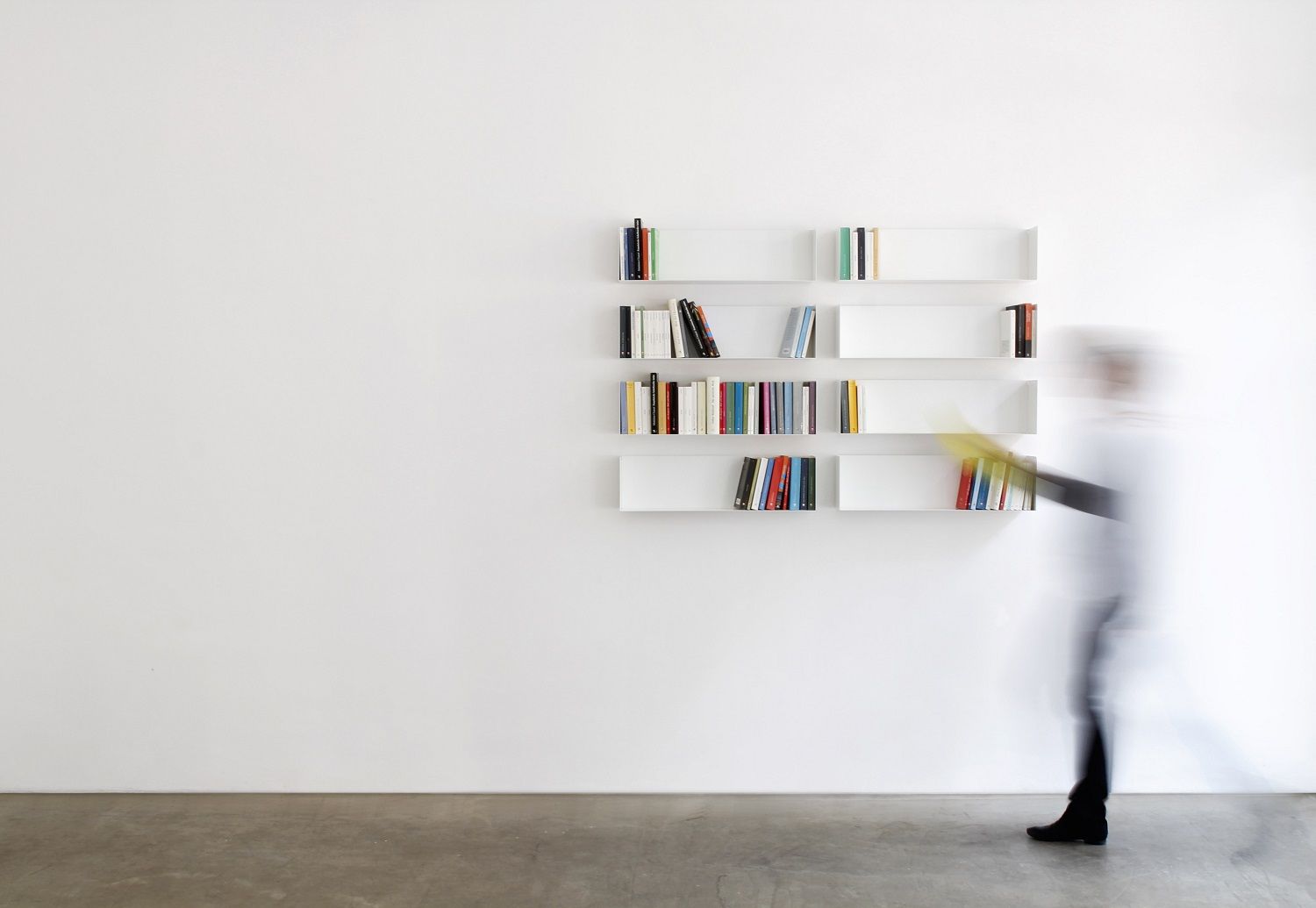 Weißes Taschenbuchregal a Linea1 von Müller Möbelwerkstätten an einer weißen Wand mit Büchern.