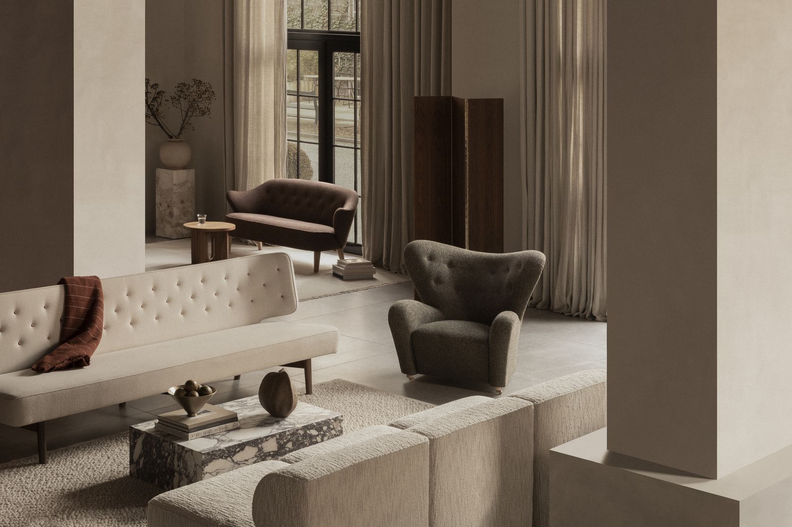Audo Ingeborg Sessel aus braunem Stoff in einem stilvollen Wohnzimmer mit Sofas und Dekoration.