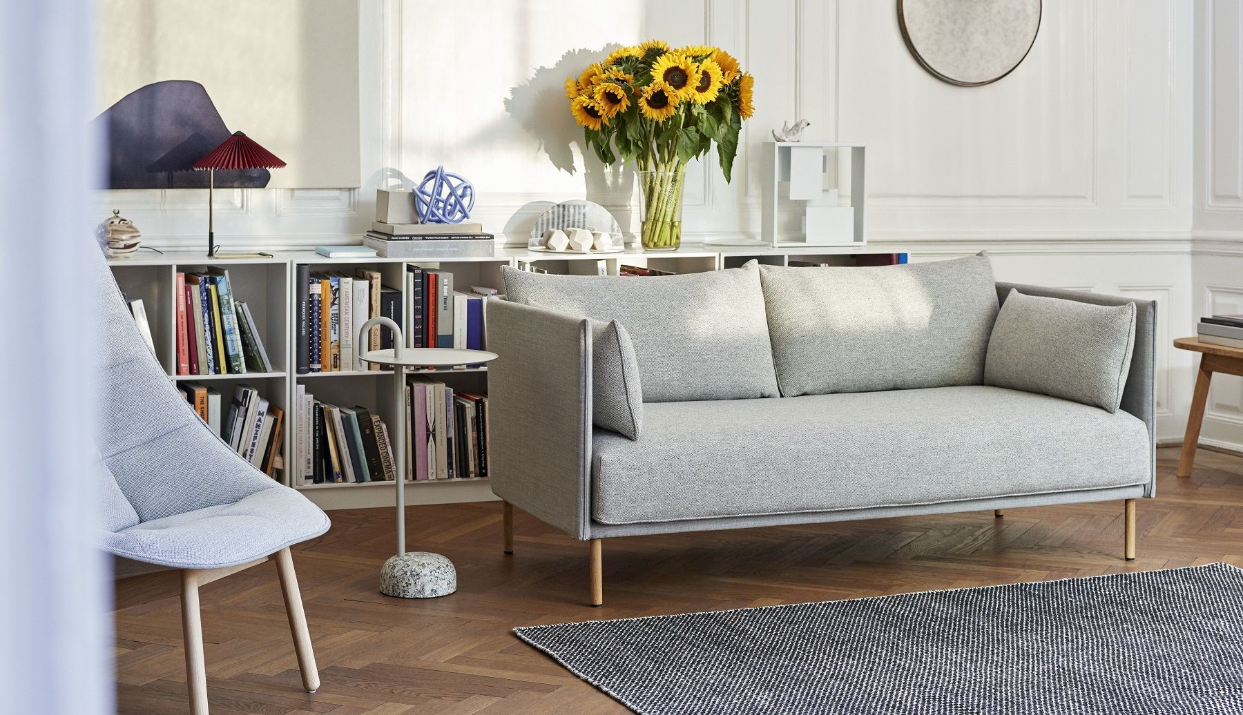 Heller Wohnraum mit Hay Bowler Beistelltisch, grauem Sofa, Bücherregal und Holzboden für modernes Interior Design.