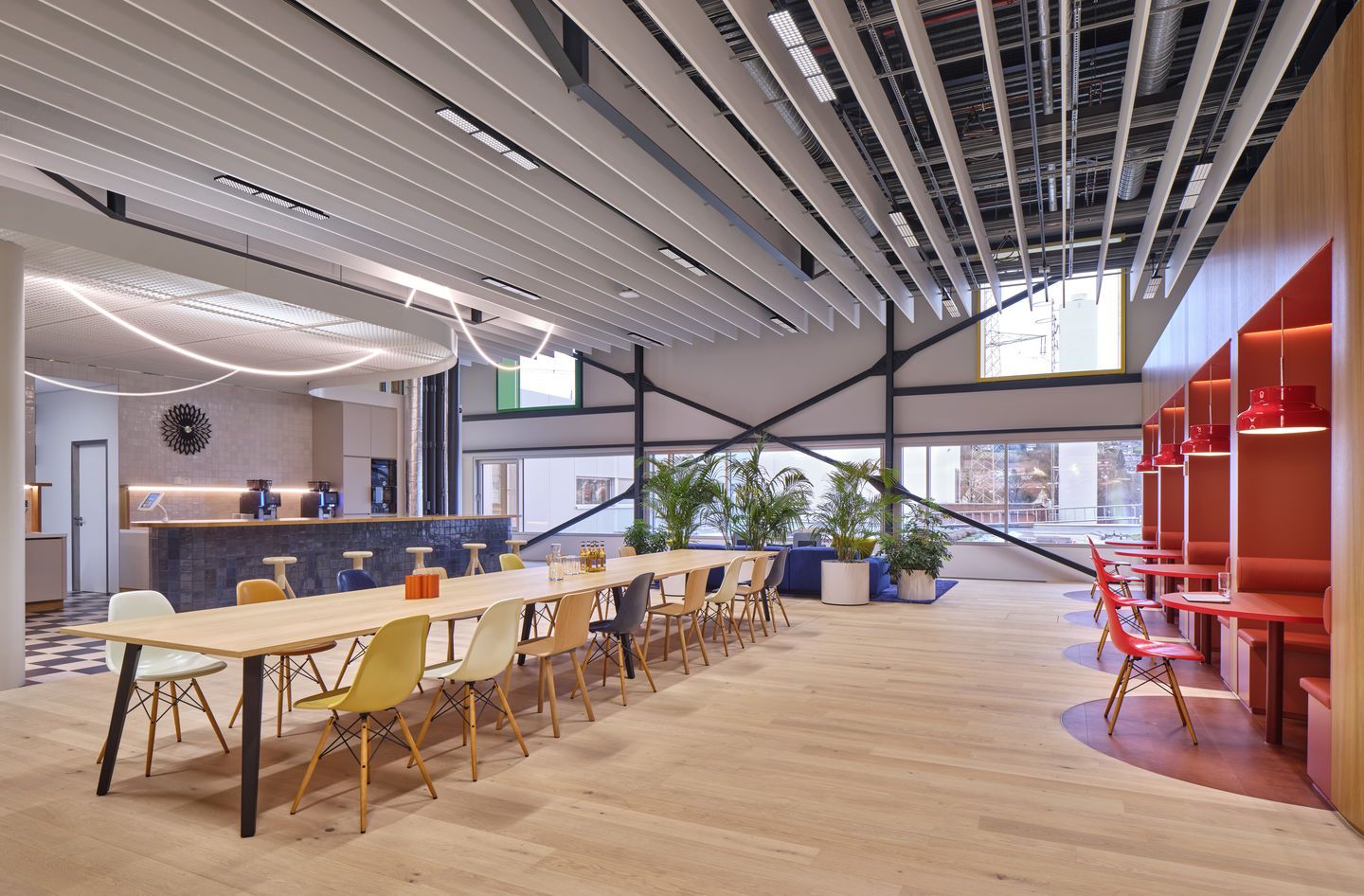 Helle Büroraum-Szene mit langer Tischreihe mit Eames DSW Stühlen und Sitzpolstern von Vitra.