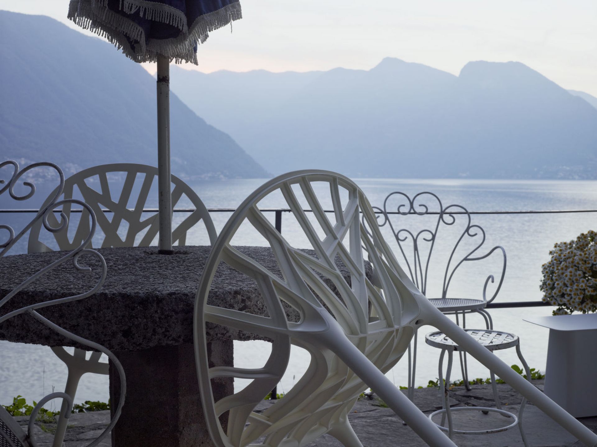 Nahaufnahme von Vitra Beistelltisch und Stühlen aus Metall auf einer Terrasse mit Seeblick.