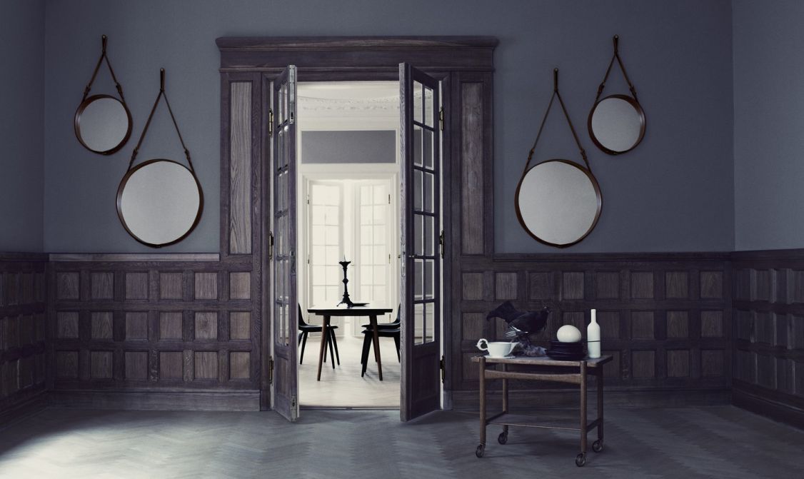Zwei Gubi Adnet Circular Wandspiegel mit Lederriemen in einem eleganten, dunklen Interieur.