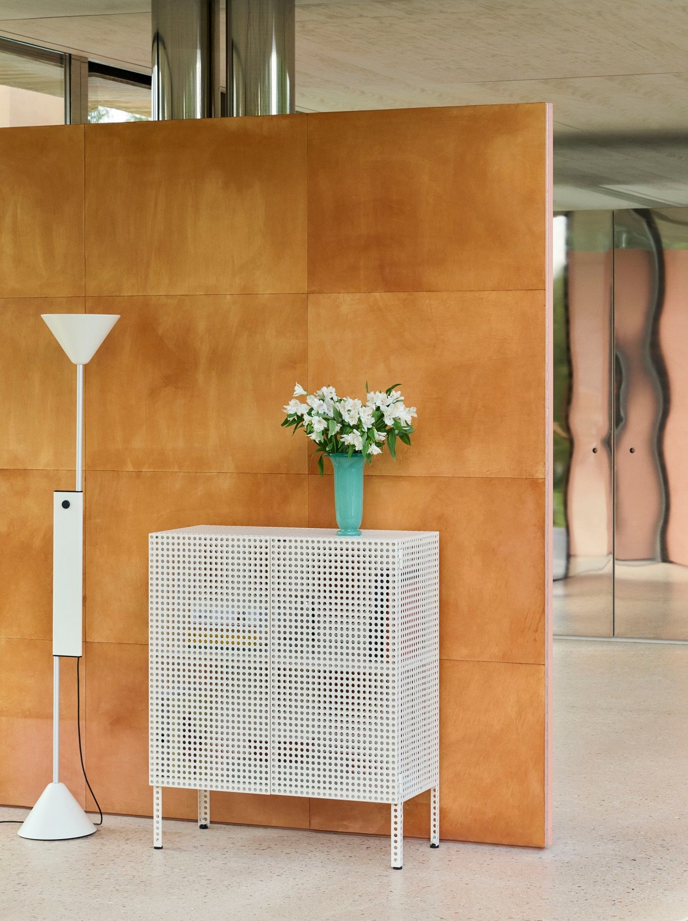 Weiße Twist Stehleuchte von Hay neben einem weißen Metallschrank mit Blumen in modernem Interieur.
