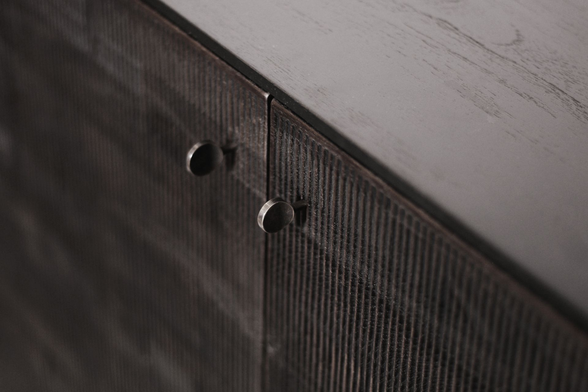 Detailaufnahme des Ethnicraft Teak Grooves Schrankes mit gerillten Türen und runden Metallgriffen.
