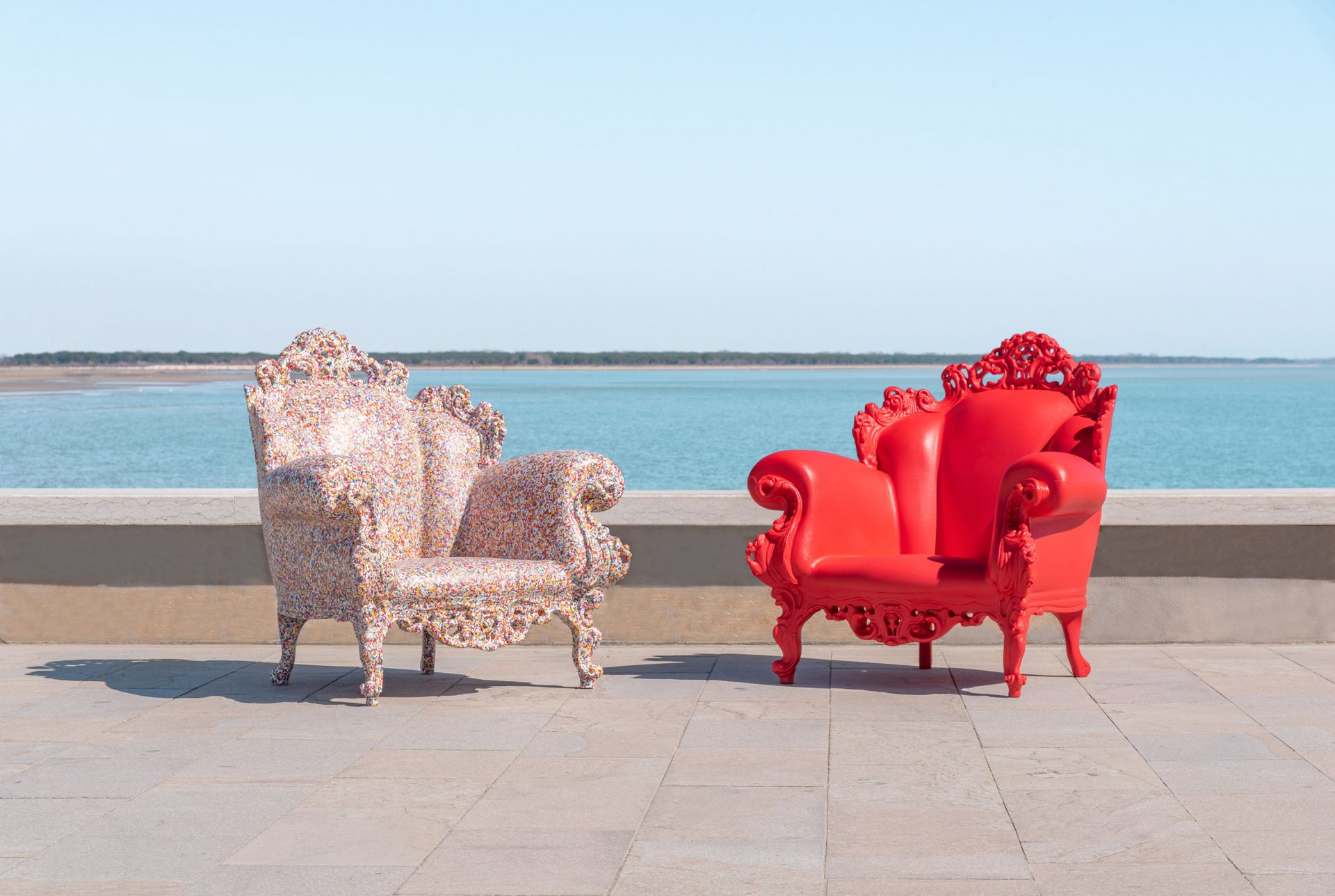 Zwei Magis Proust Sessel Outdoor, einer rot, einer bunt, vor Meer und blauem Himmel.