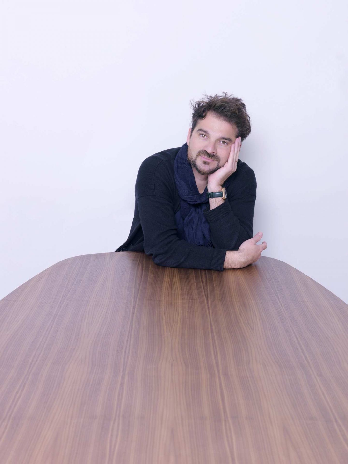 Mann lehnt am Fritz Hansen Analog Tisch aus Holz, modernes Design für Esszimmer und Büro.