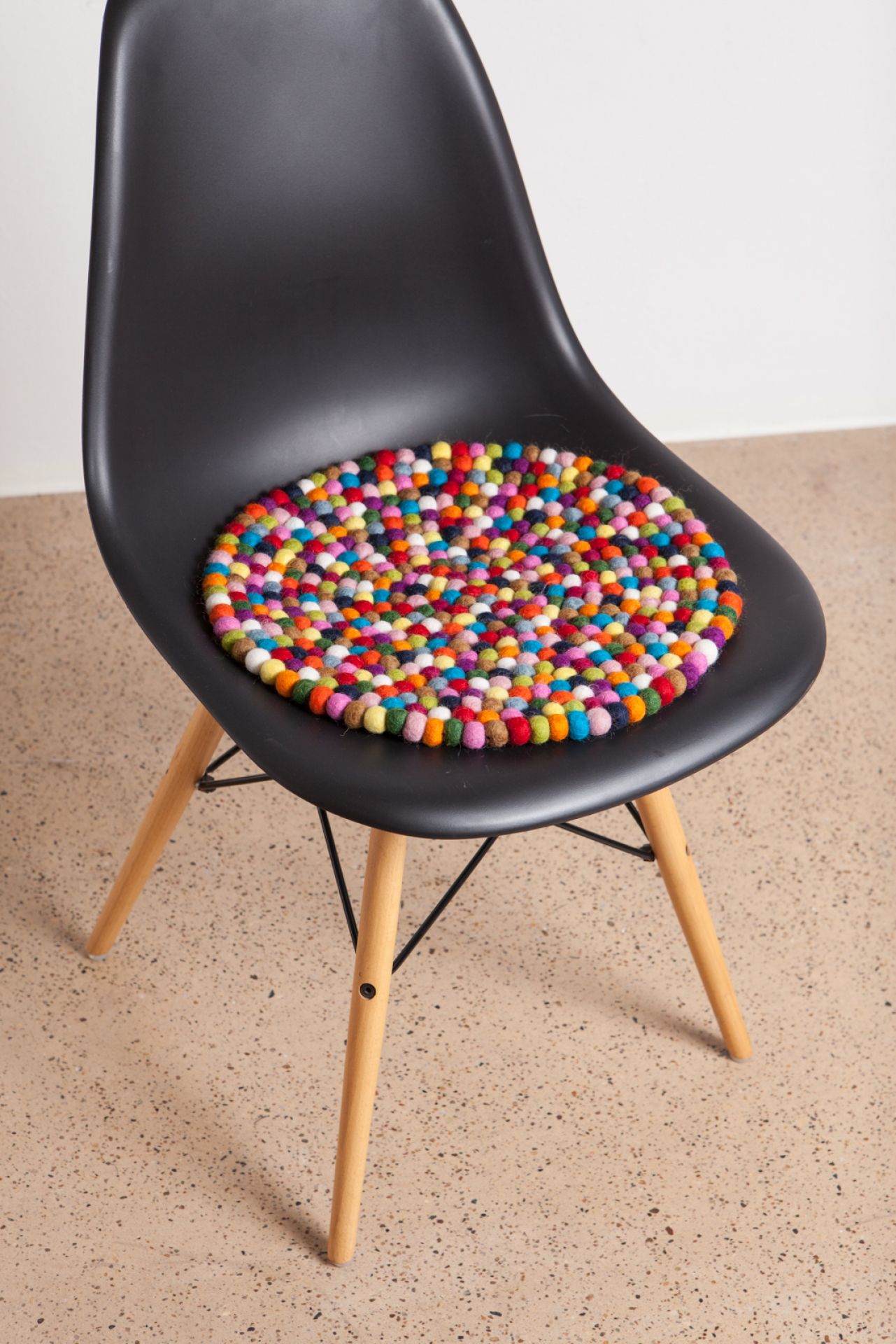Myfelt Filzkugel Sitzauflage auf einem schwarzen Stuhl, runde Stuhlauflage mit bunten Filzkugeln, 36 cm Durchmesser.