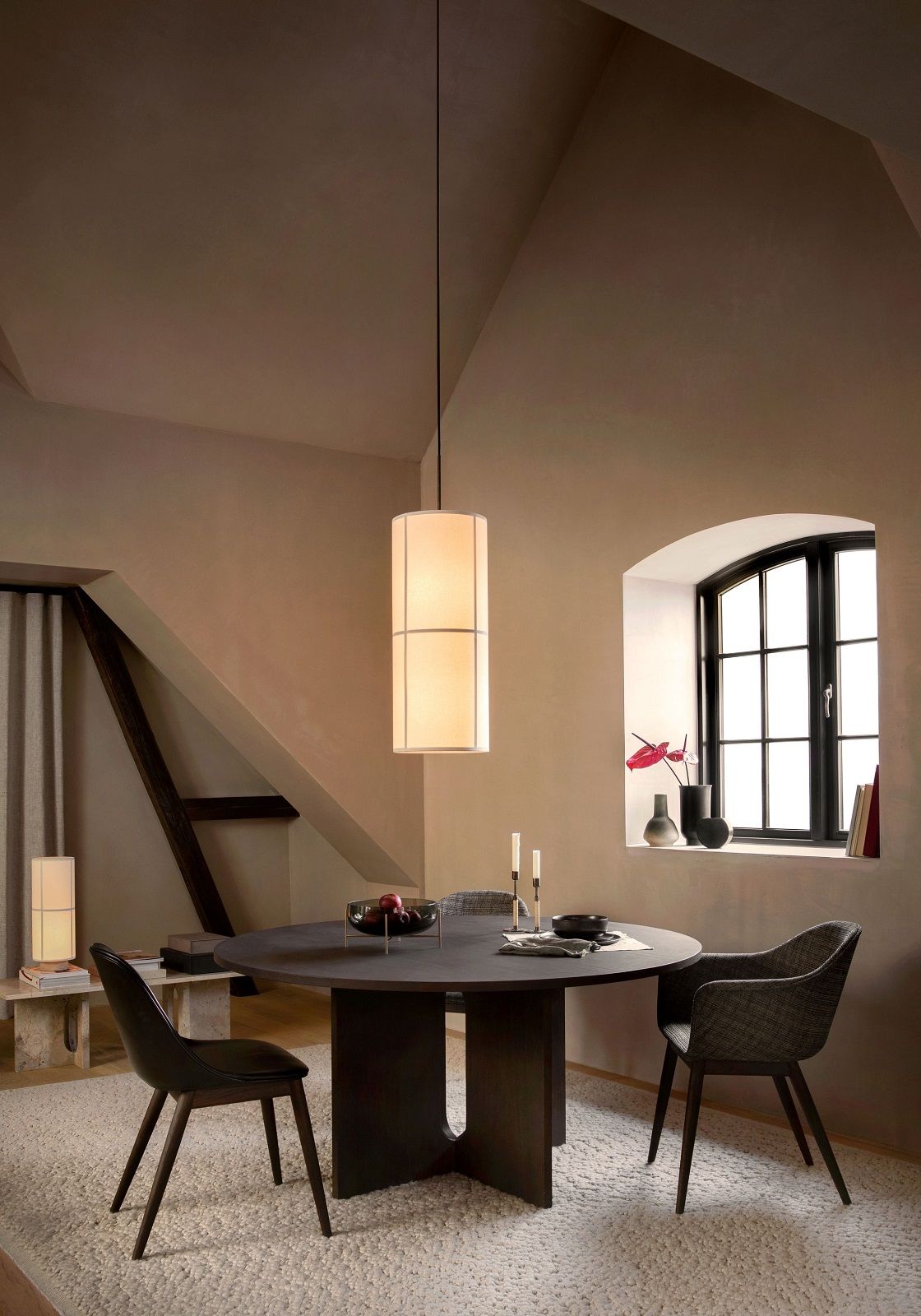 Audo Copenhagen Gravel Rug Teppich in einem Esszimmer mit dunklem Holztisch und Stühlen.