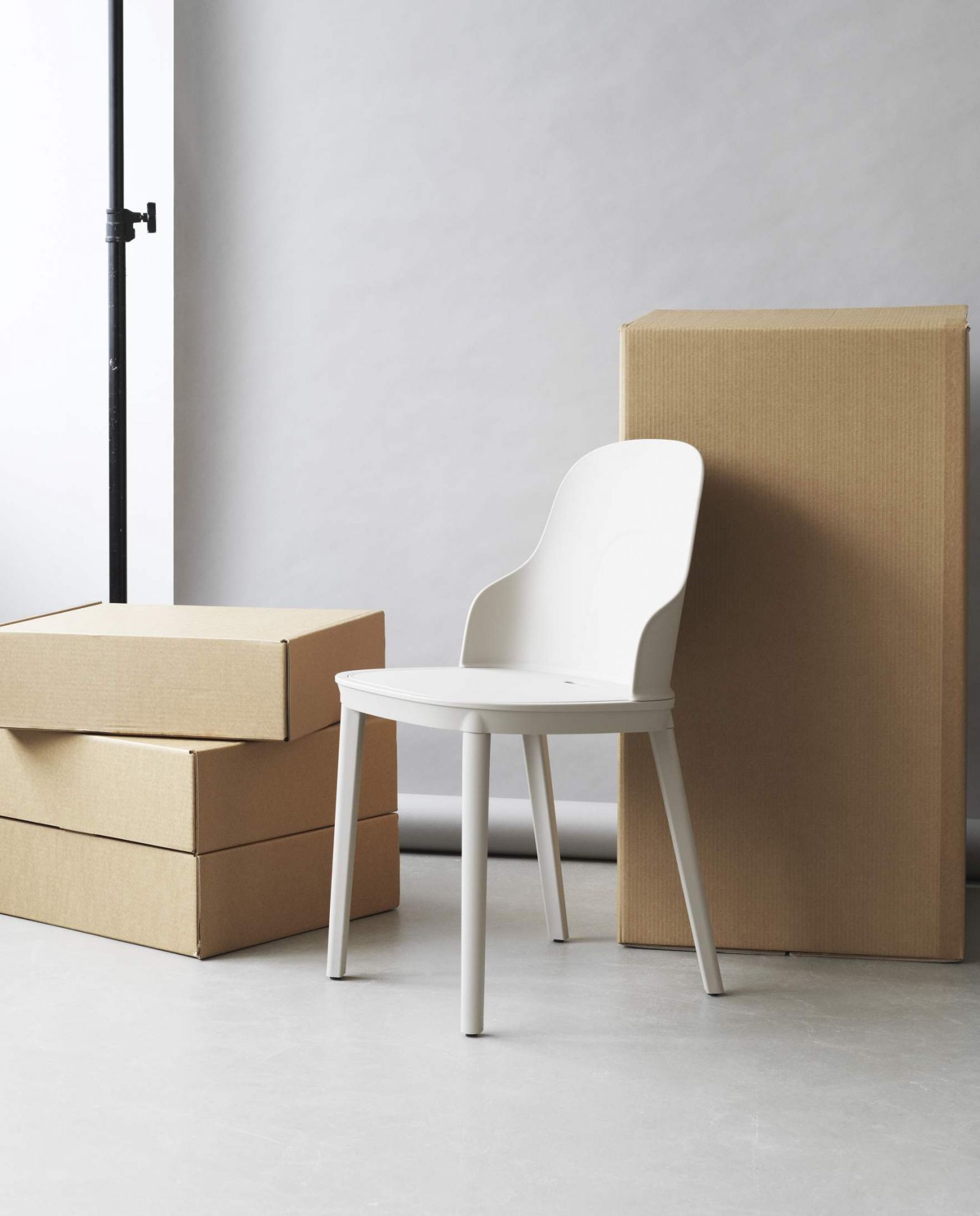 Weißer Allez Chair PP Stuhl von Normann Copenhagen neben Kartons im minimalistischen Studio.