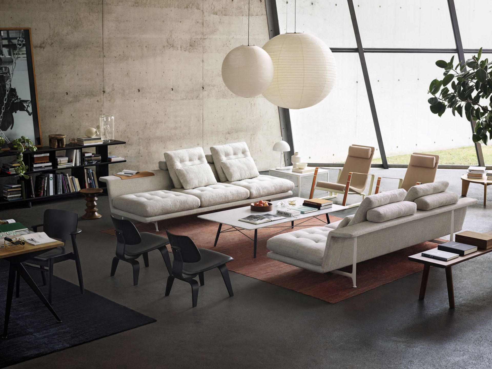 Helle Akari Pendelleuchten von Vitra über modernem Wohnzimmer mit Sofas, Sesseln und minimalistischem Design.