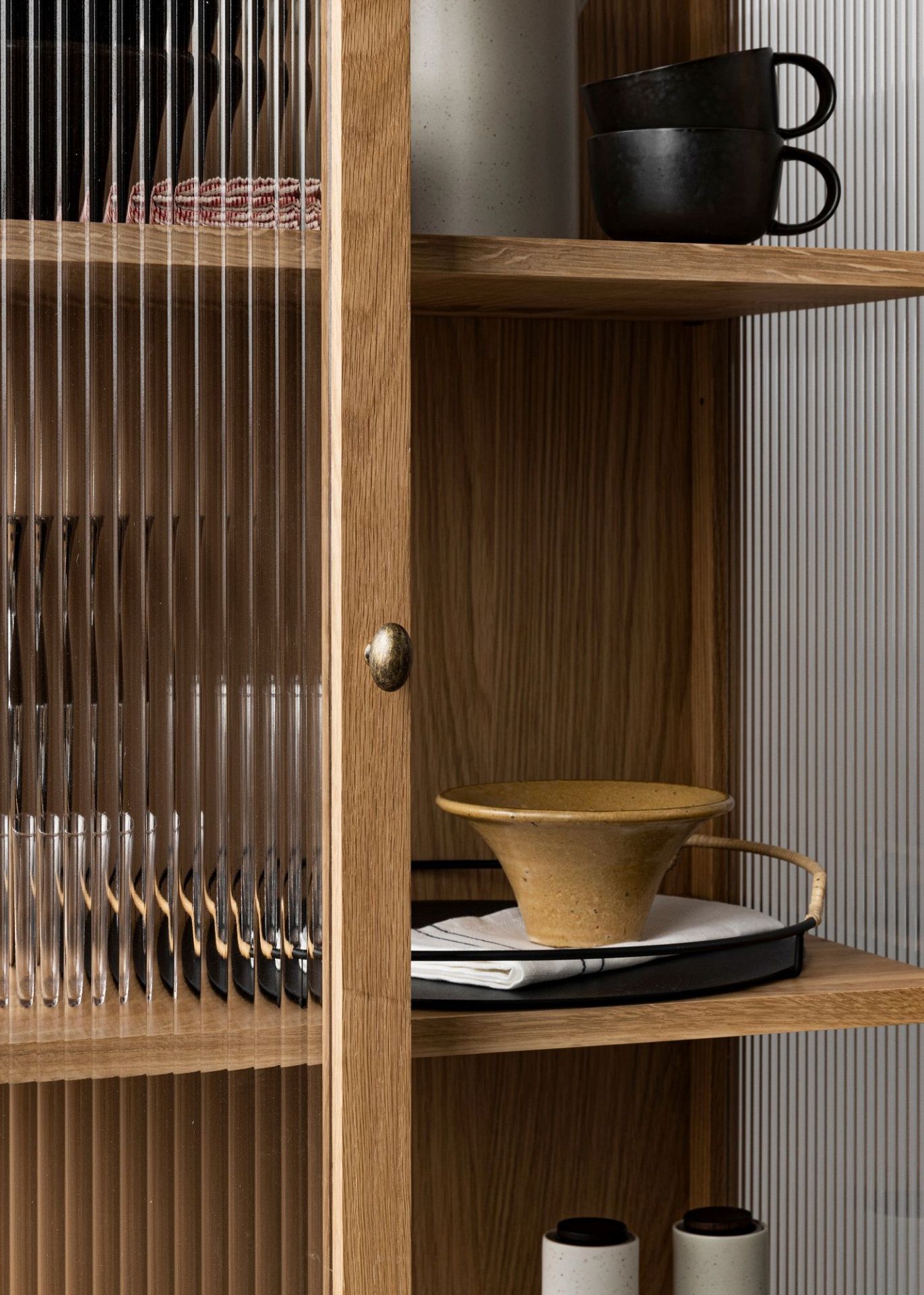 Detailaufnahme des Curiosity Cabinet Schranks von Audo Copenhagen mit Glasfront und Eichenholz Regalböden.