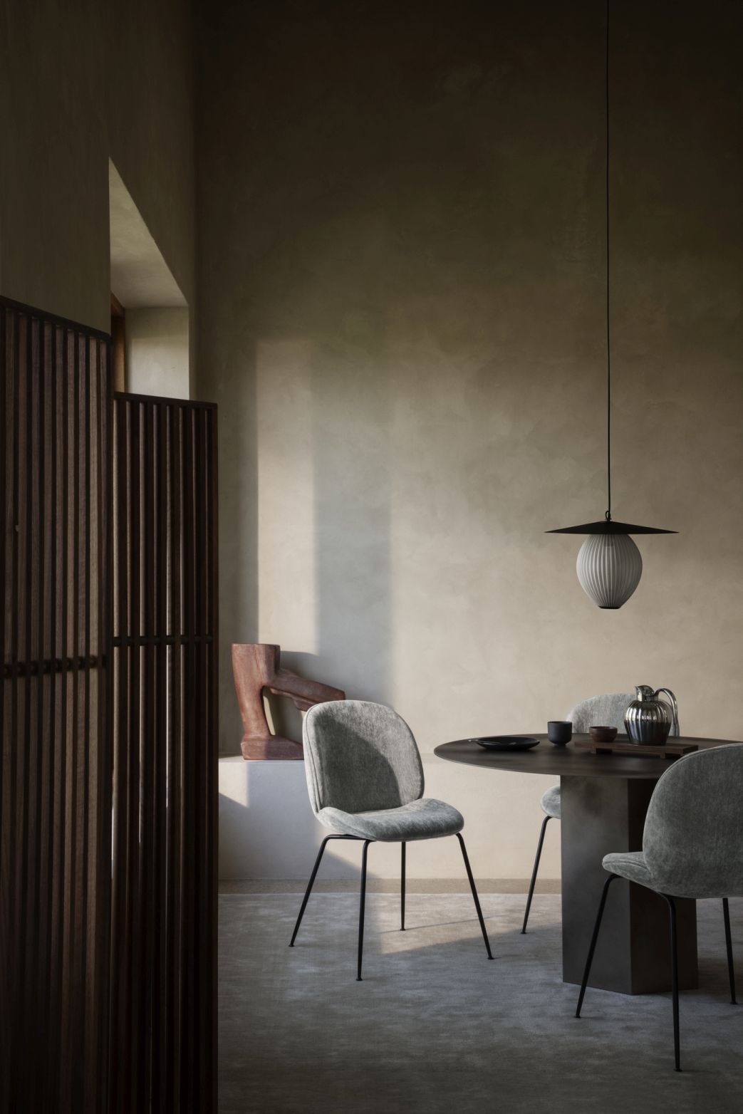 Runder Gubi Esstisch "Epic" aus dunklem Holz mit Stühlen und Pendelleuchte in minimalistischem Interieur.
