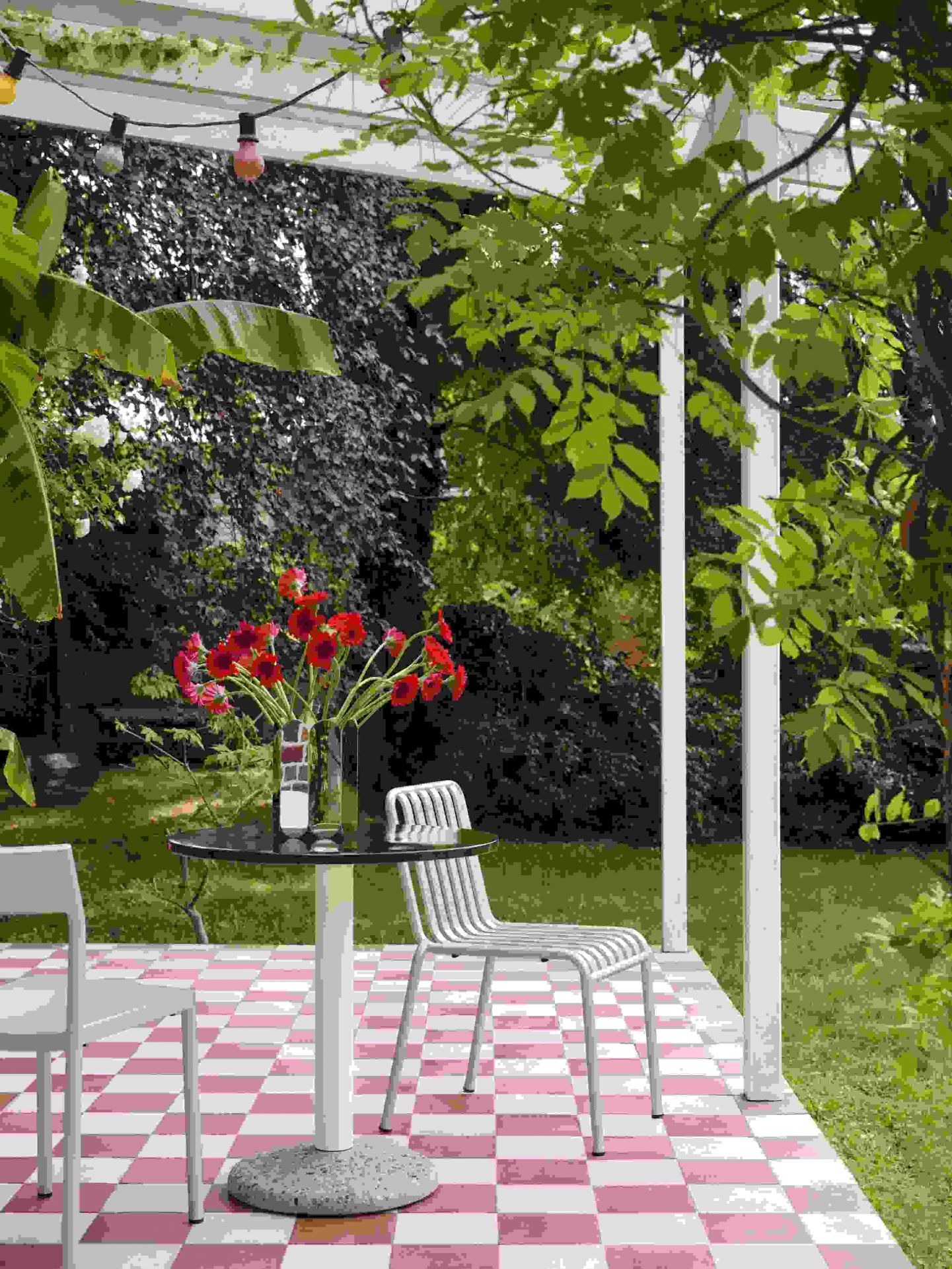 Helle Terrasse mit Hay Stühlen, rundem Tisch mit Blumen in der Arcs Vase L Mirror.