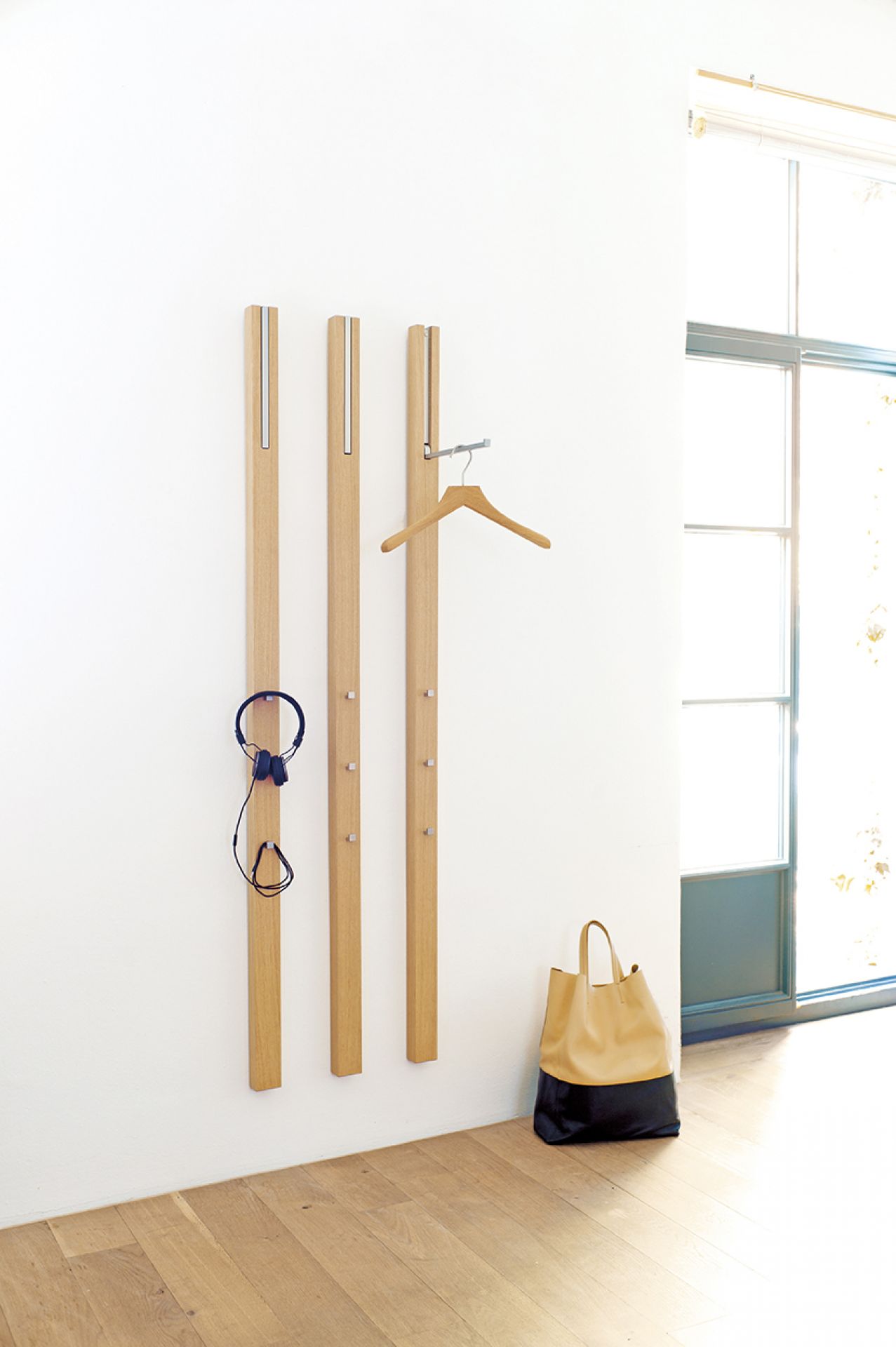 Line Garderobenelement KIESELSTEIN von Schönbuch: Moderne Holzgarderobe mit Haken, Kleiderbügel und Tasche im Flur.