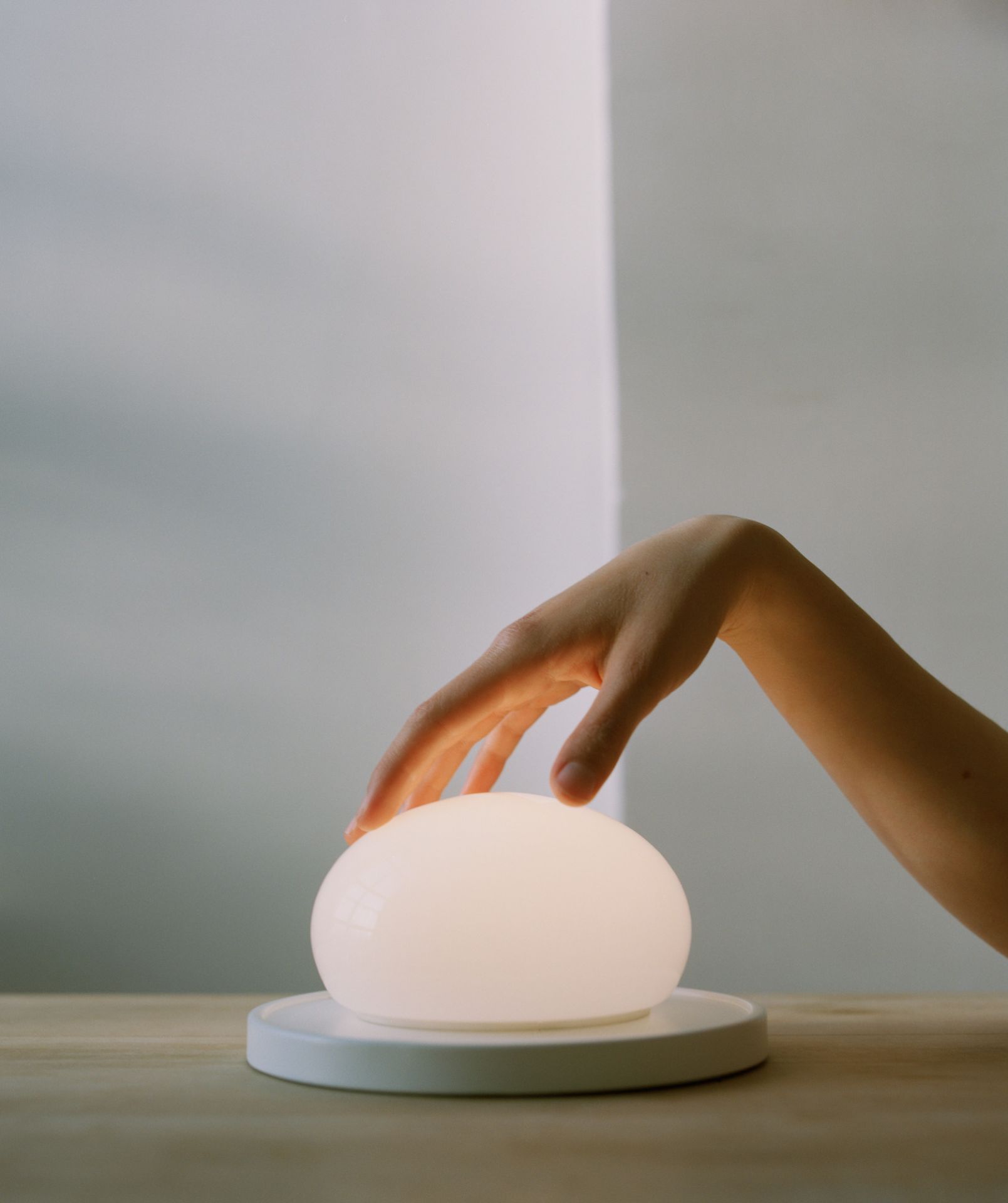 Nahaufnahme der Bolita LED Tischleuchte von Marset mit Hand auf dem Leuchtenschirm.