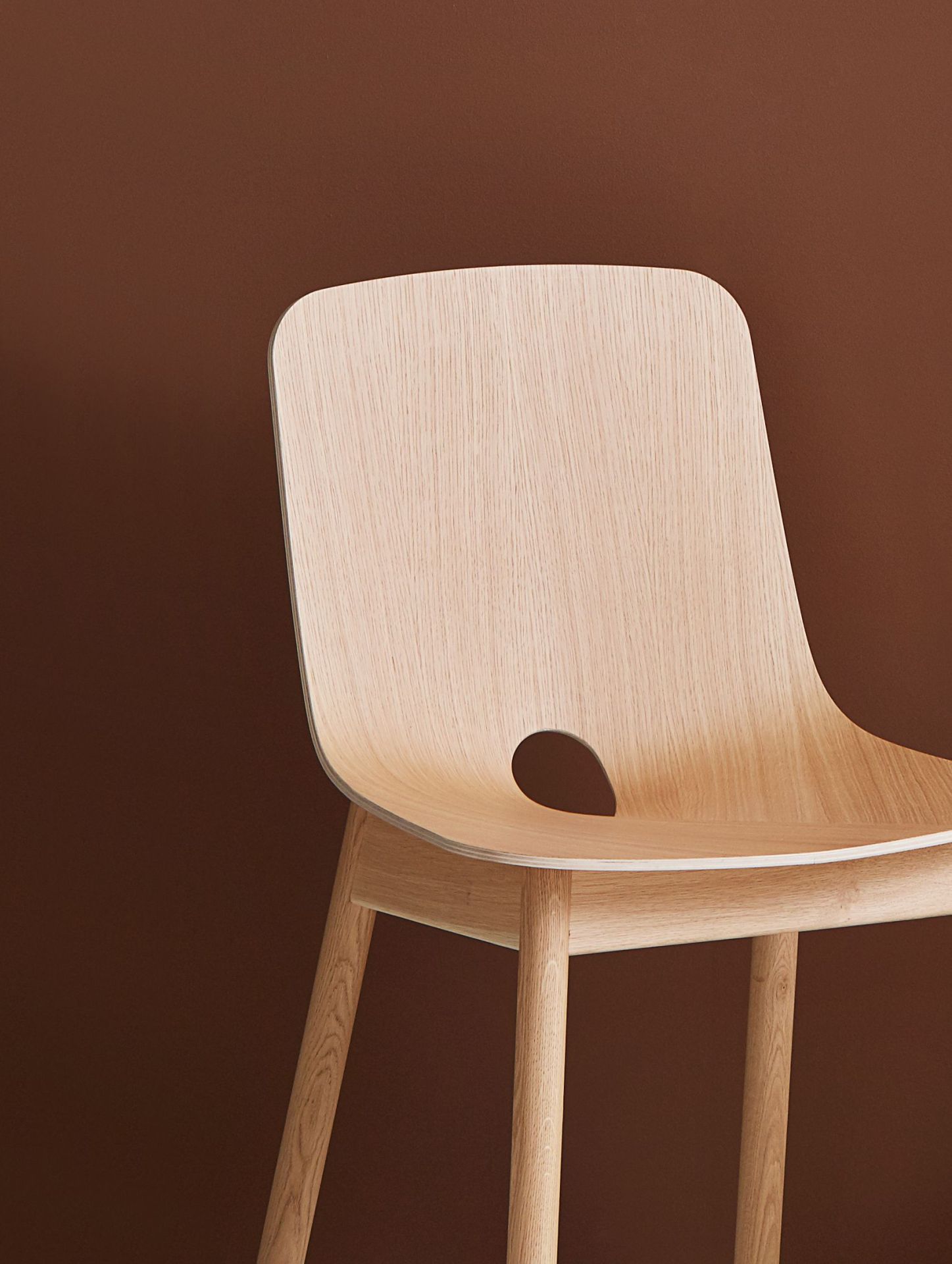Detailaufnahme des hellen Holzstuhls "Mono dining Chair" von Woud mit runder Aussparung in der Rückenlehne.