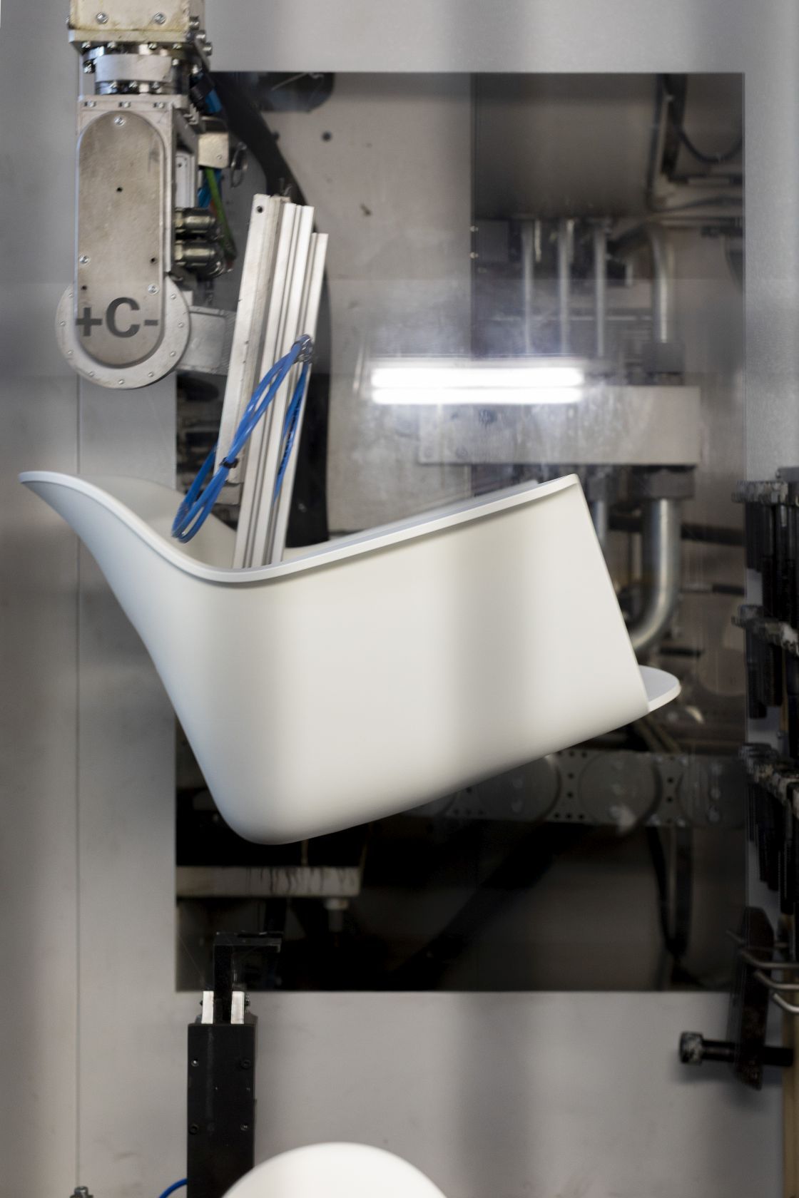 Layout Armchair 234 von Hay in der Produktion, weiße Sitzschale wird von einem Roboterarm gehalten.