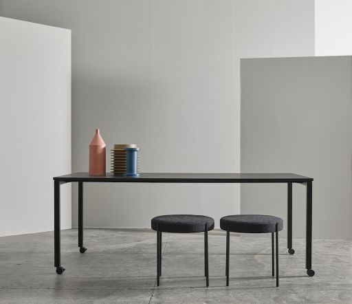 Zwei graue Series 430 Hocker von Verpan vor einem schwarzen Tisch in einem minimalistischen Raum.