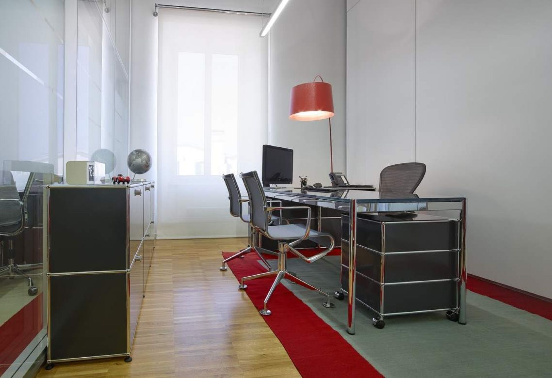 Büro mit USM Haller Rollcontainer in Enzianblau unter einem Schreibtisch, Stauraum und Büromöbel.