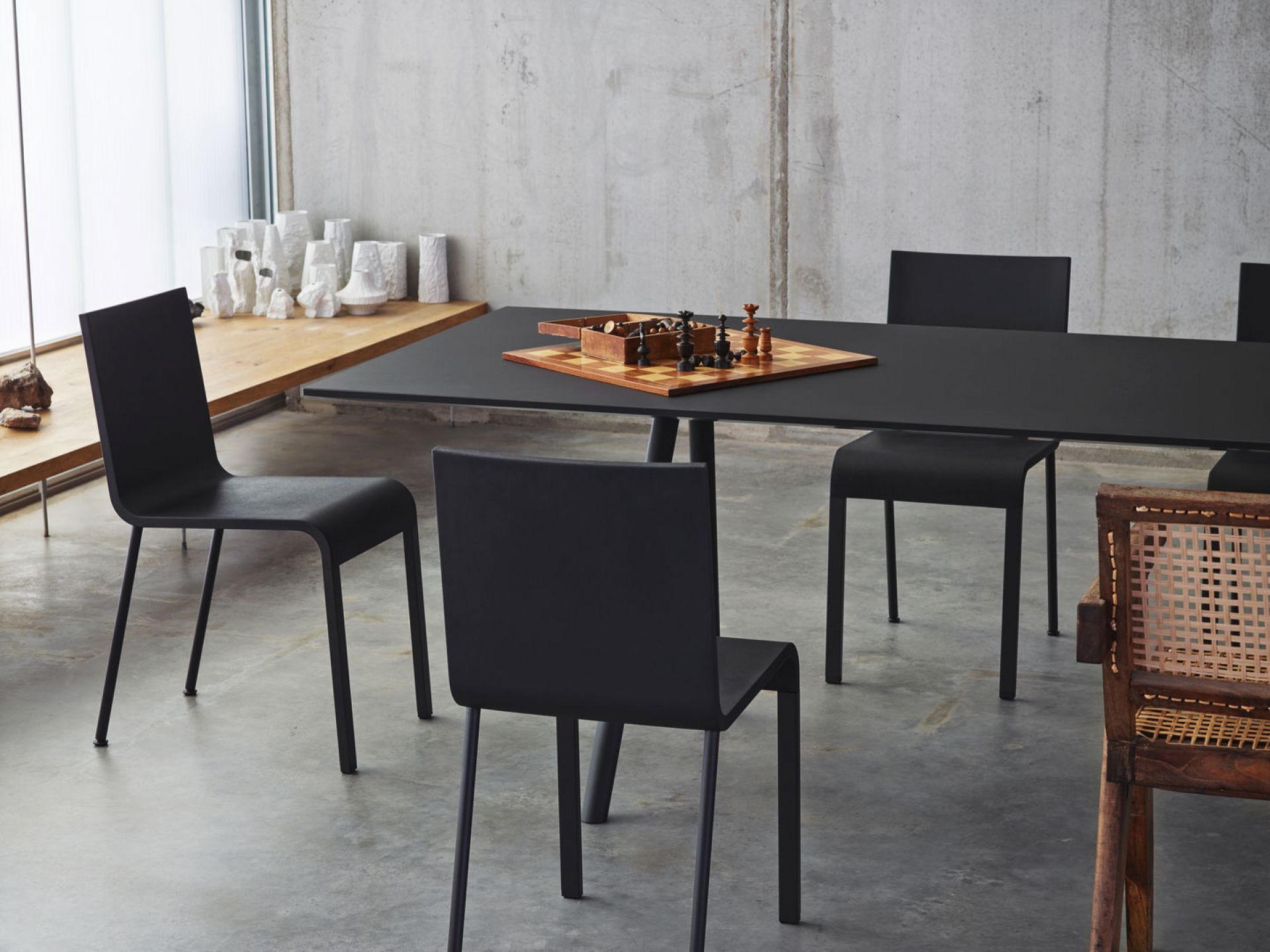 Schwarzer .03 Stuhl von Vitra an einem Esstisch mit Schachbrett in einem modernem Interieur.
