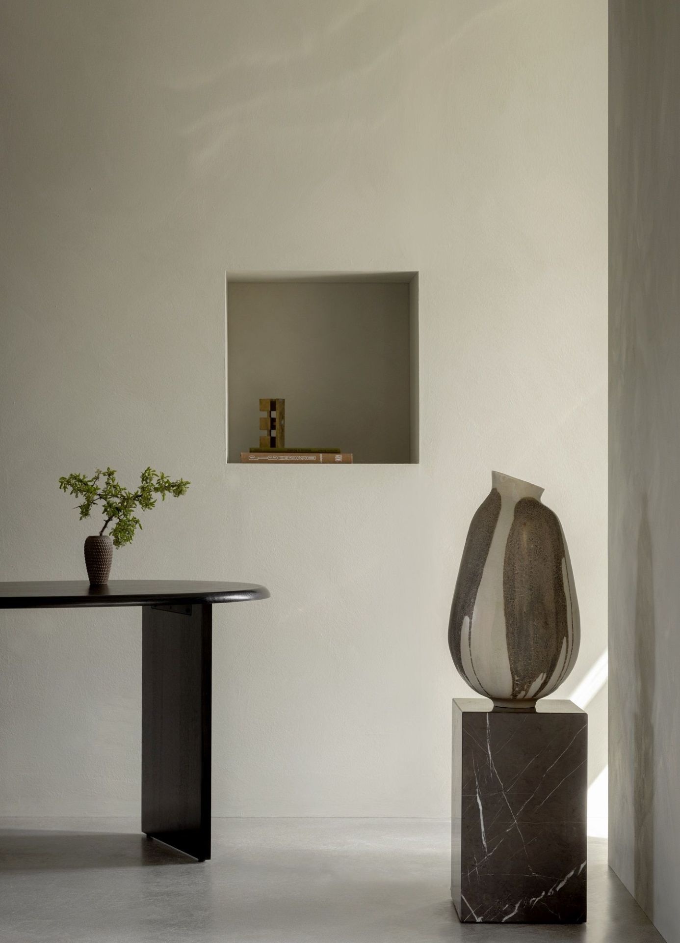 Audo Copenhagen Eclipse Desk Schreibtisch aus dunklem Holz mit minimalistischer Dekoration in einem hellen Raum.
