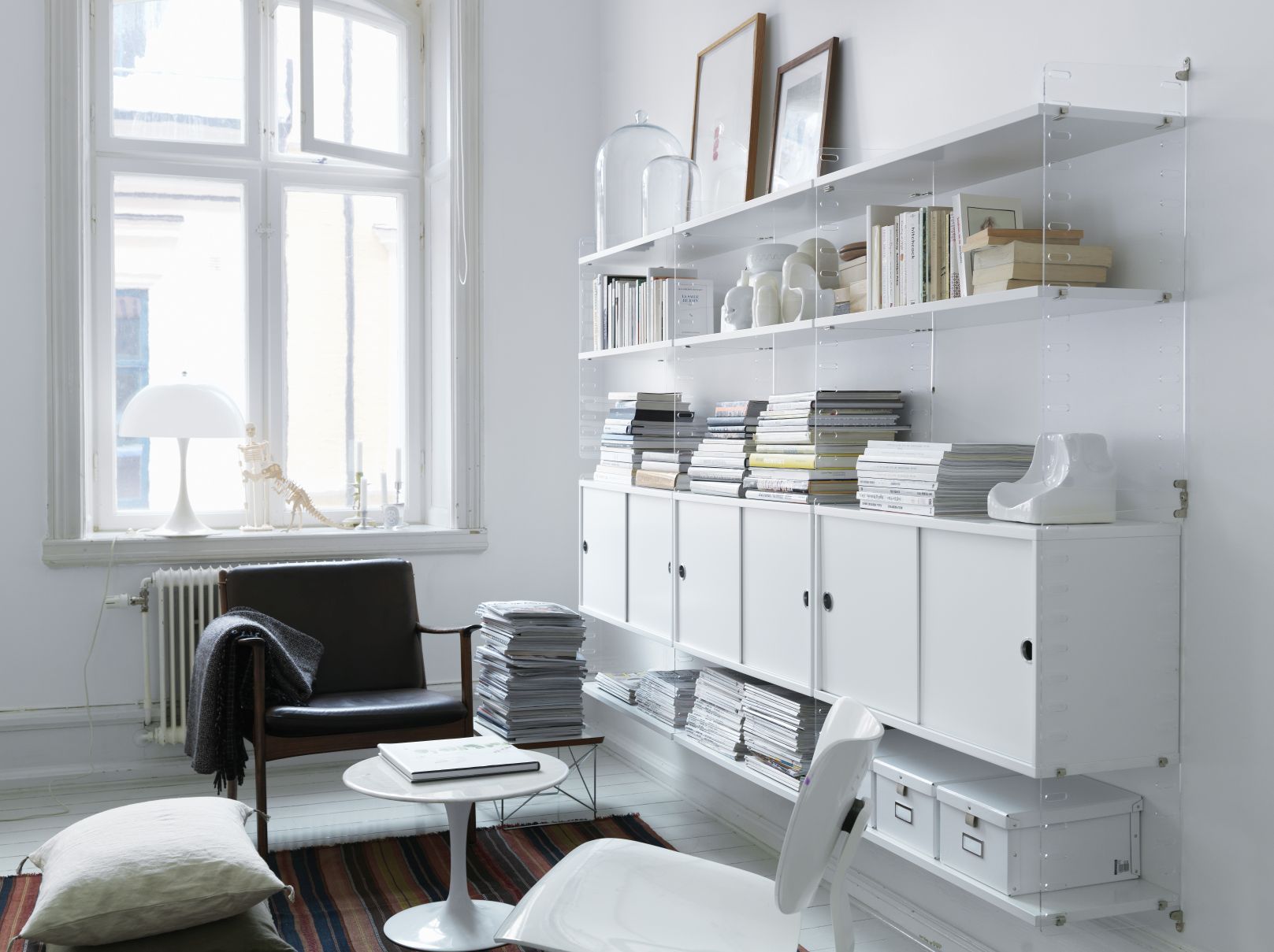 String Furniture Regalsystem mit weißen Schiebetüren. Modernes Design für Wohnzimmer und Büro.