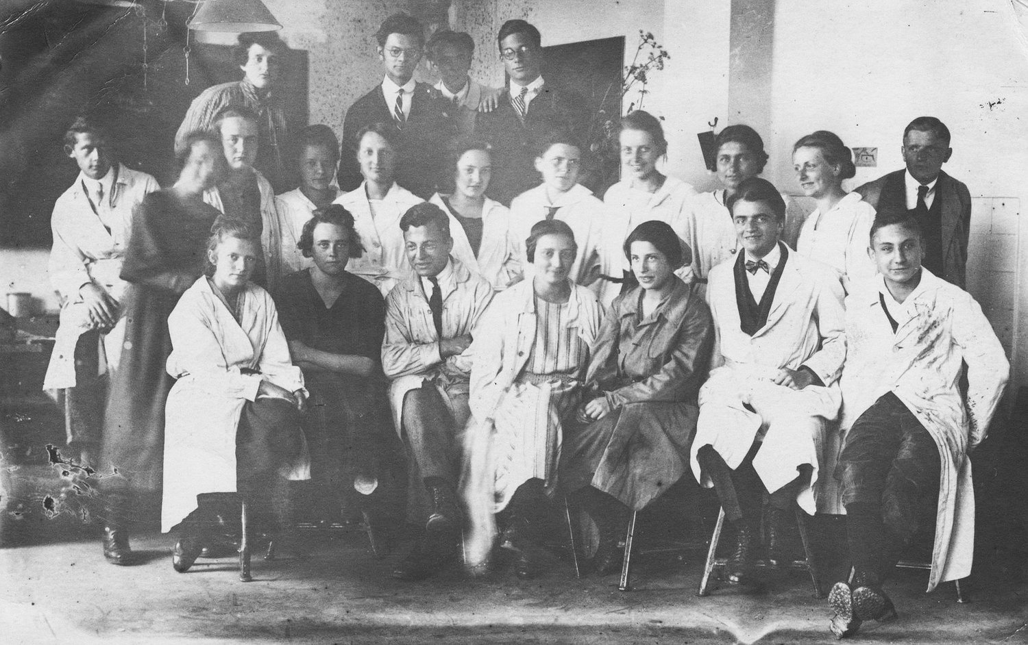 Historisches Schwarzweißfoto einer Gruppe von Menschen, die auf Rowac Schemel Barhockern sitzen.