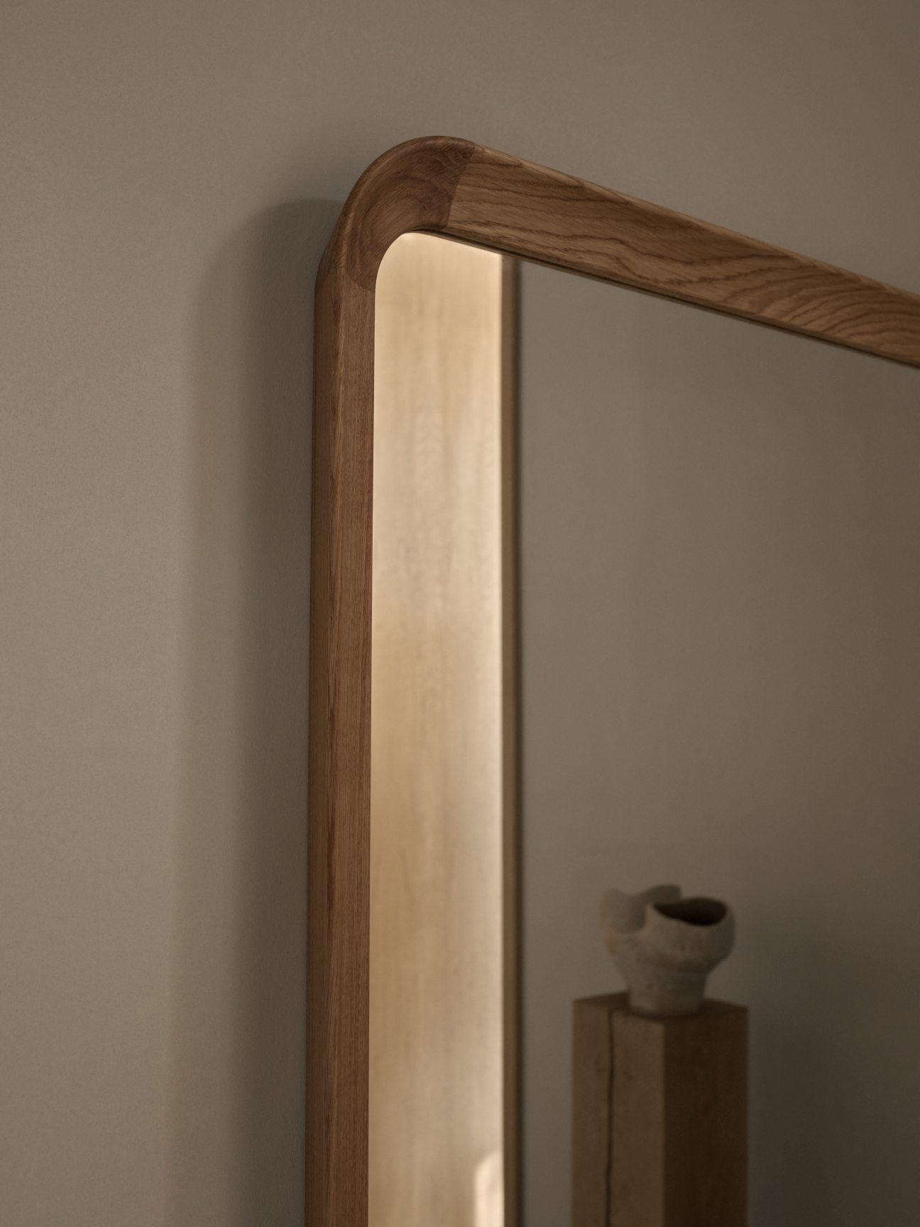 Detailaufnahme des VLA62 Radio House Spiegels von Carl Hansen & Søn mit Holzrahmen und Beleuchtung.