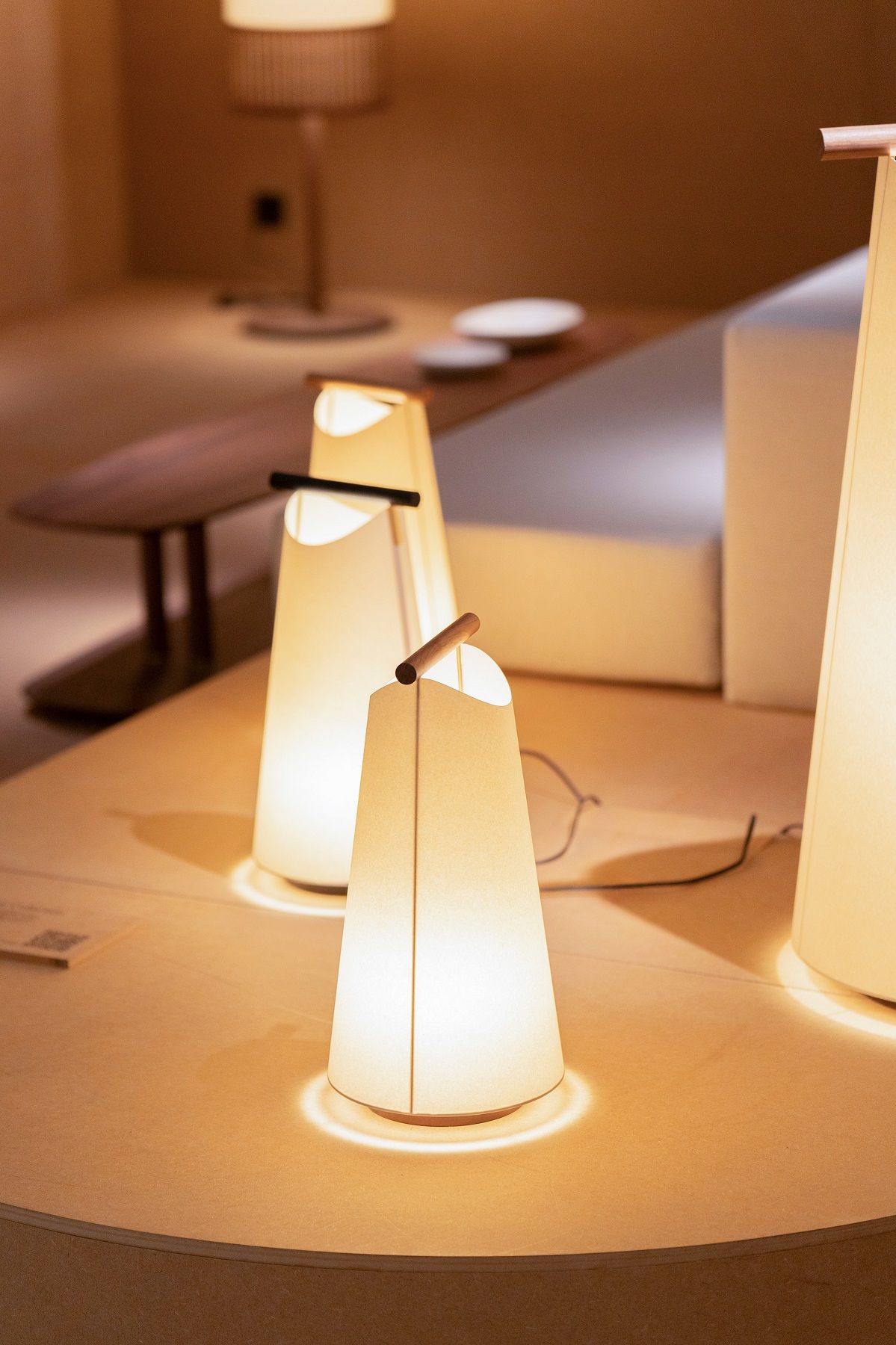 Nahaufnahme von drei beleuchteten Catay Tischleuchten von Nomon, moderne Akku-Tischlampen mit warmem Licht.