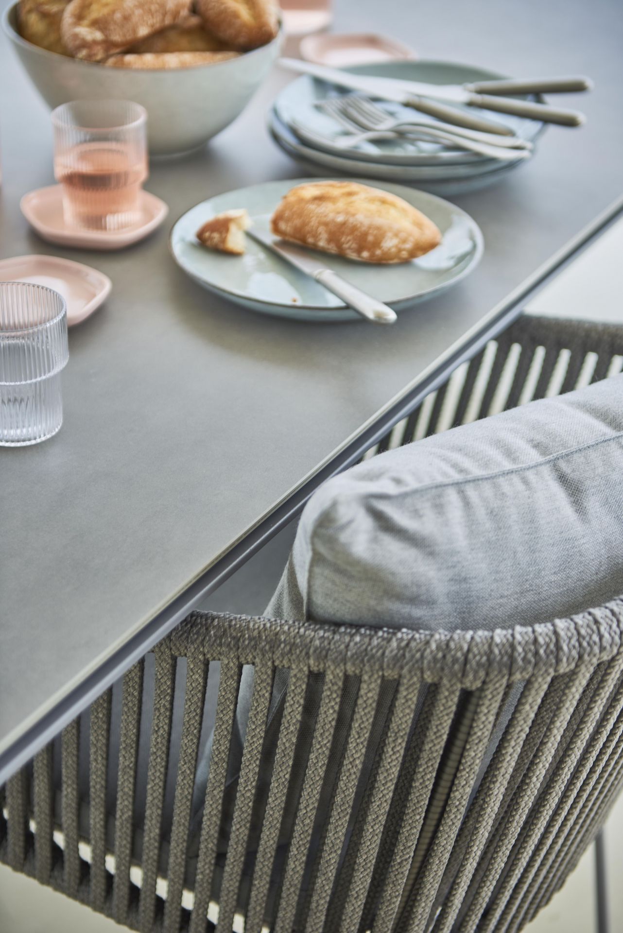 Detailaufnahme des Cane-Line Pure Outdoor Esstisches mit Geschirr und Stuhl mit grauer Kordel.