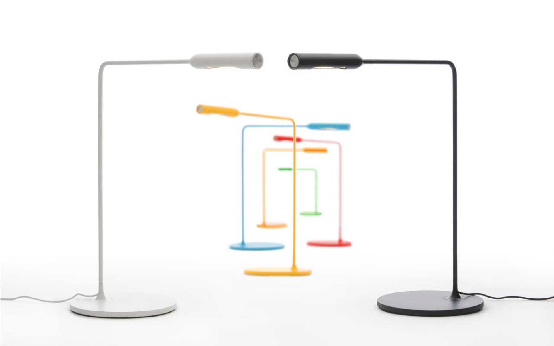 Flo Desk Tischleuchte Lumina in Weiß und Schwarz, weitere Farben im Hintergrund.