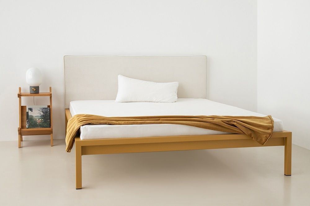 Pure Bett mit sandgoldenem Stahlrahmen und Polsterkopfteil, modernes Schlafzimmerdesign.