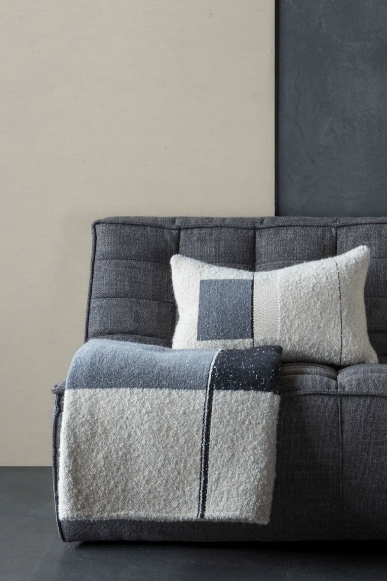 Urban Überwurf von Ethnicraft: Grauer Wollüberwurf und passendes Kissen mit geometrischem Muster auf Sofa.