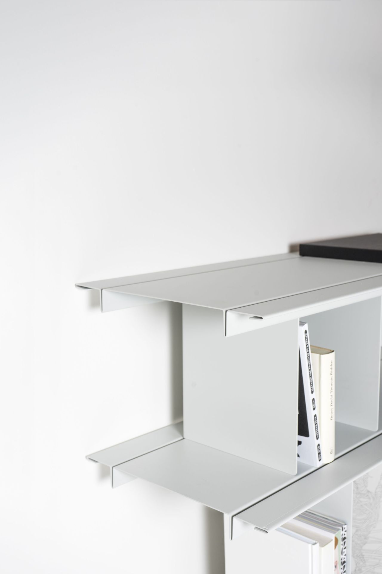 Detailaufnahme des Zoll D Regals von Nils Holger Moormann, ein minimalistisches, weißes Wandregal mit Büchern.