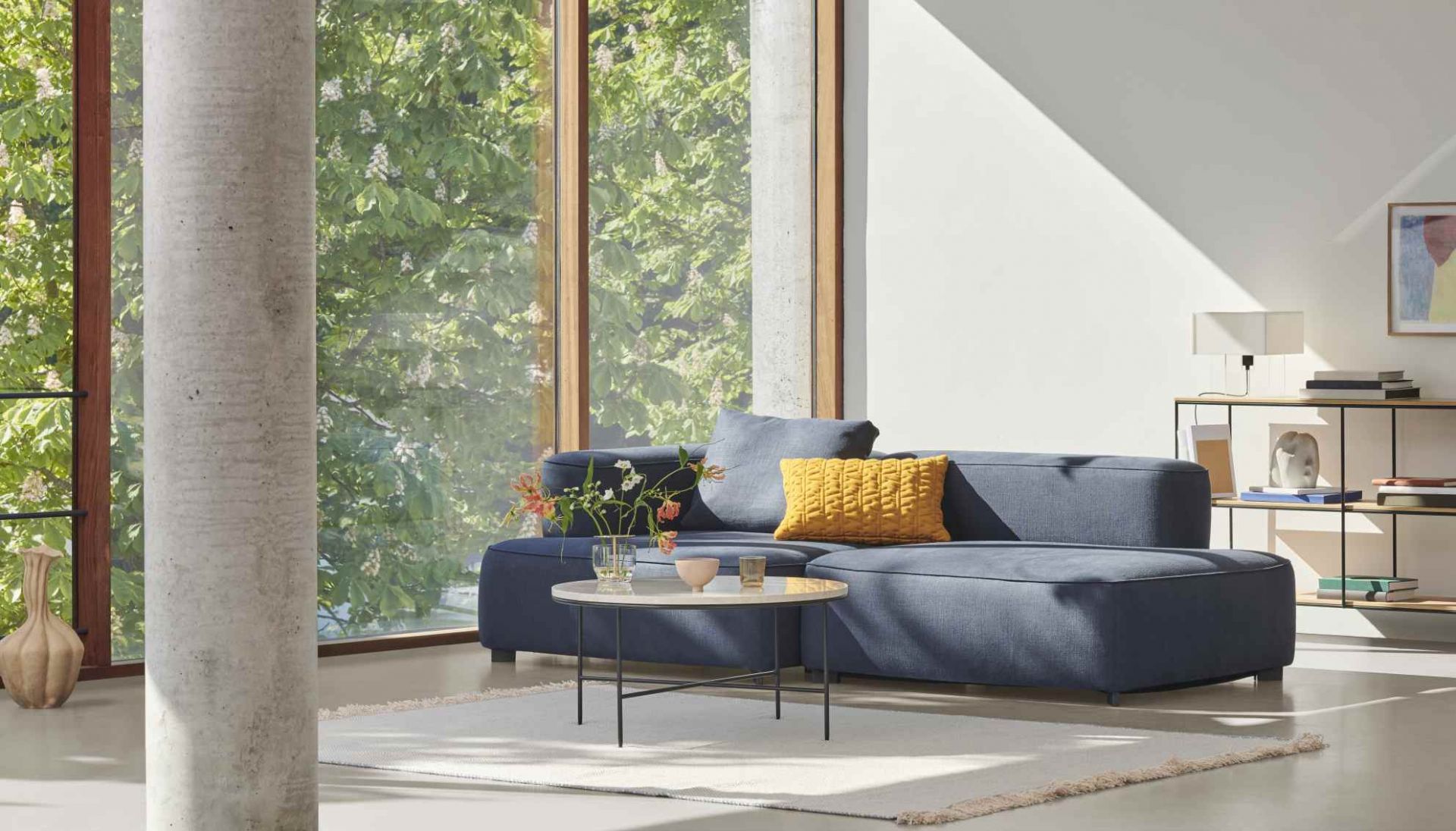 Moderner Wohnraum mit blauem Sofa, Fritz Hansen Couchtisch Planner und minimalistischem Design.