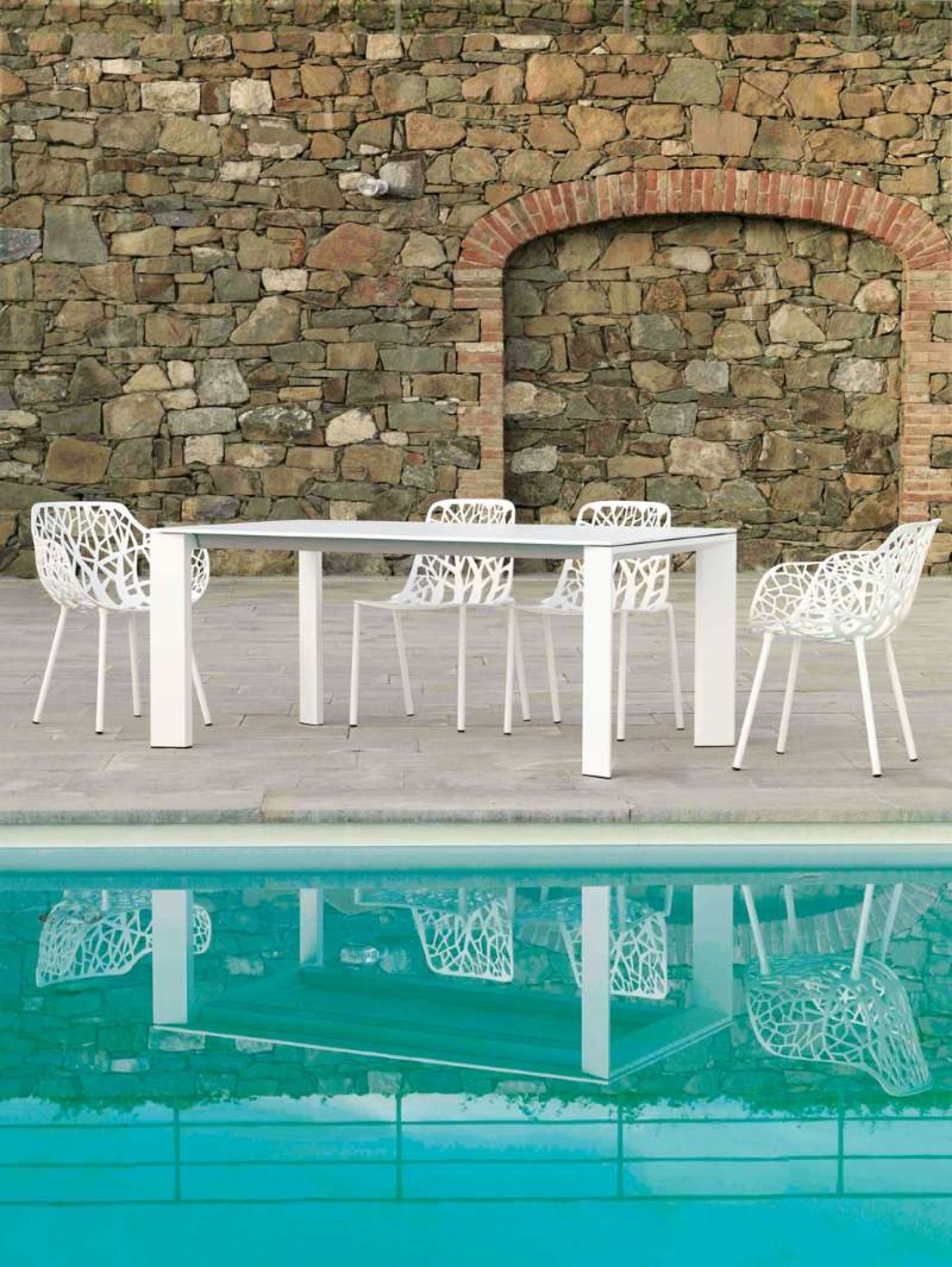 Grande Arche Outdoor Tisch von Fast mit weißen Stühlen am Pool.
