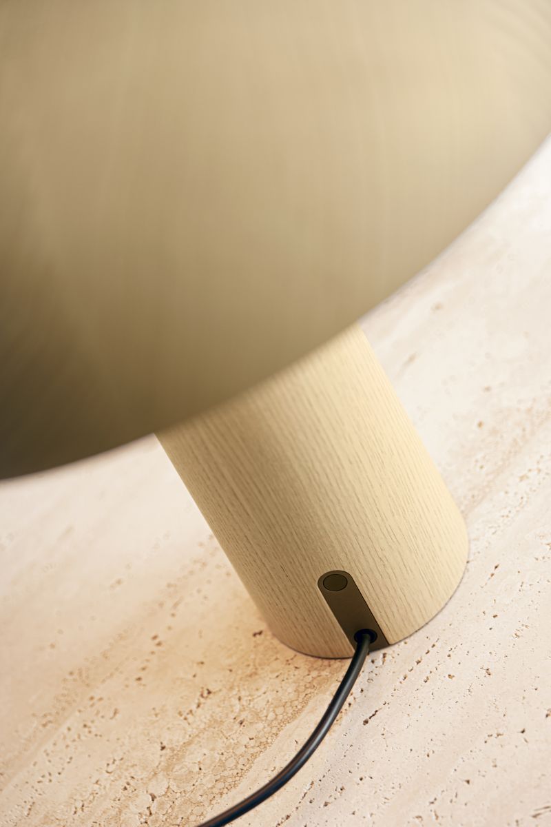 Detailaufnahme der ClassiCon Forma Tischleuchte mit Holzfuß und beigem Lampenschirm auf beigem Untergrund.