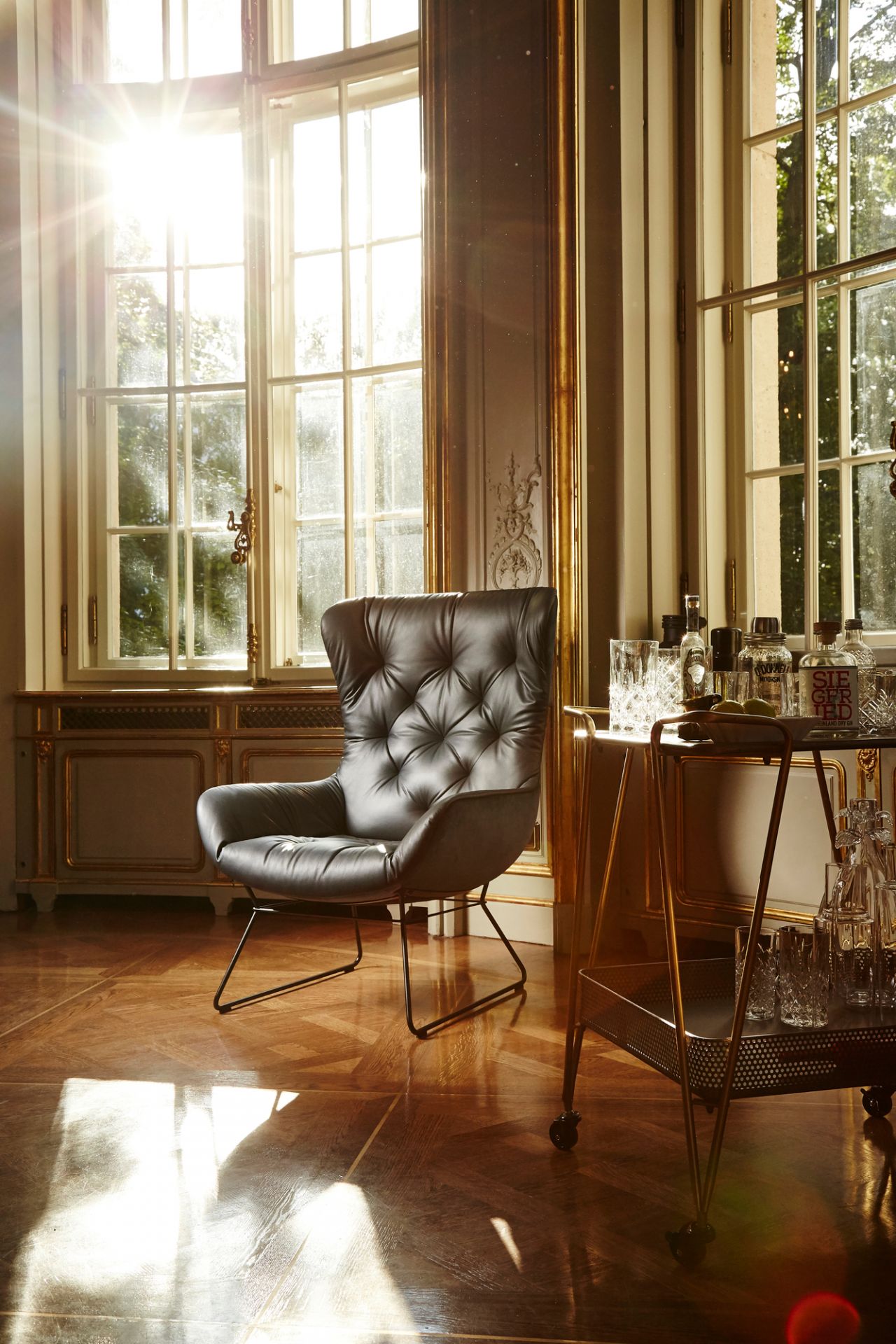 Leder Ohrensessel Leya Wingback von Freifrau Manufaktur in edlem Ambiente mit Barwagen und Tageslicht.