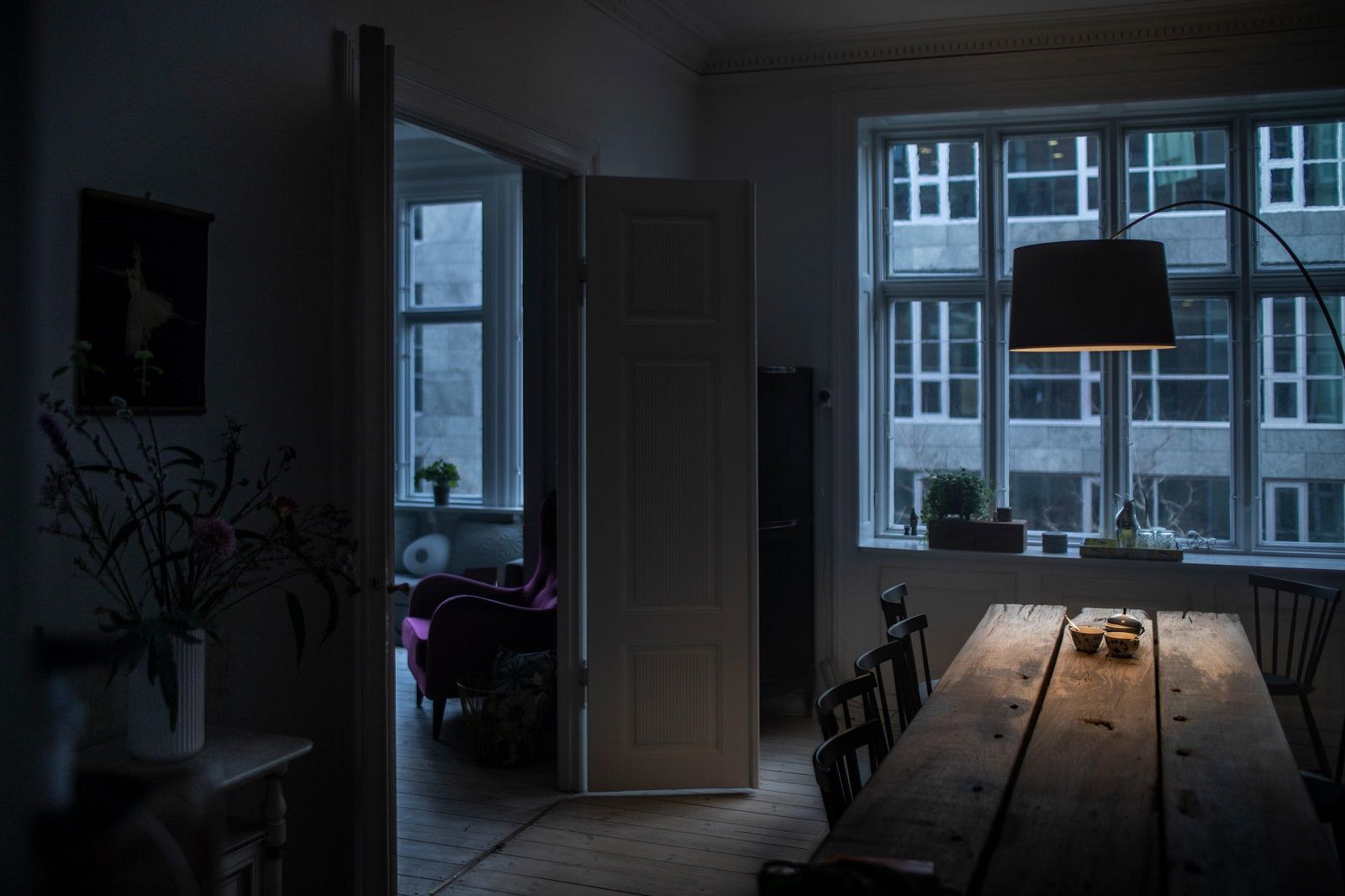 Twiggy Stehleuchte von Foscarini beleuchtet dunkles Esszimmer mit Holztisch und Fensterfront im Hintergrund.