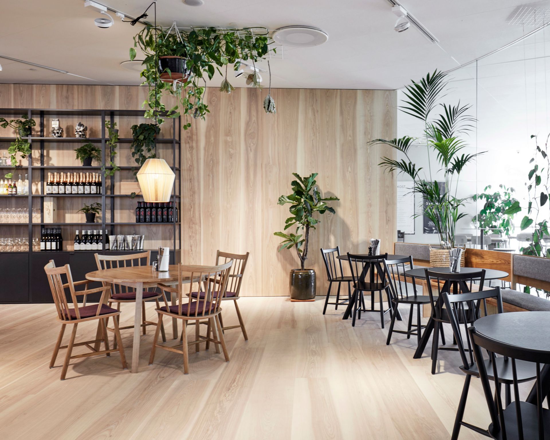 Innenansicht eines hellen Restaurants mit Holzböden und mehreren Copenhague Table CPH 20 Stehtischen von Hay.