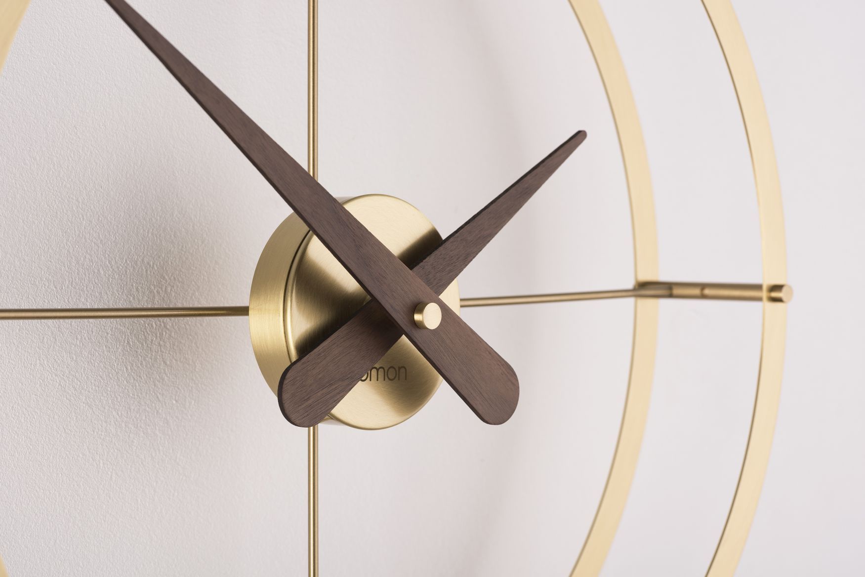 Detailaufnahme der Nomon Gold Uhr mit Holzzeigern und goldenem Rahmen.