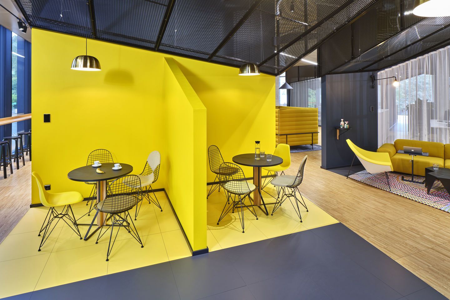 Gelber Büroraum mit Vitra Coconut Chair und Wire Chairs, moderne Büromöbel für kreative Arbeitsumgebung.