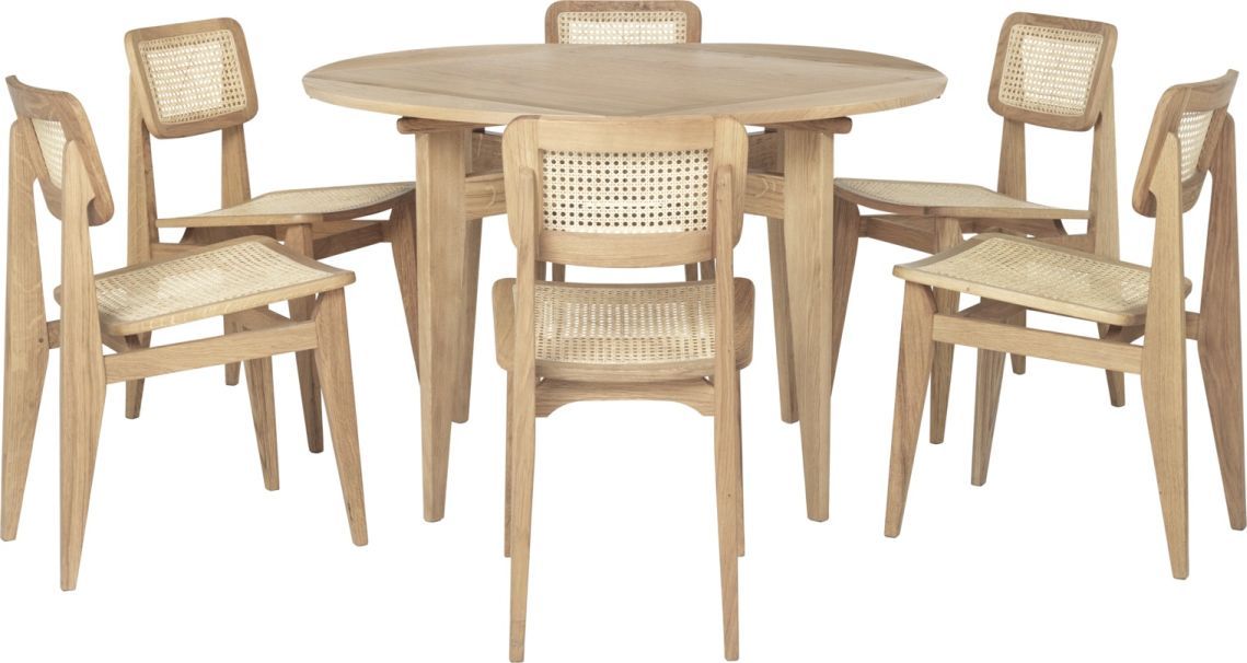 Gubi B-Table Esstisch ausziehbar mit sechs Holzstühlen mit Rattanlehne und -sitz vor weißem Hintergrund.