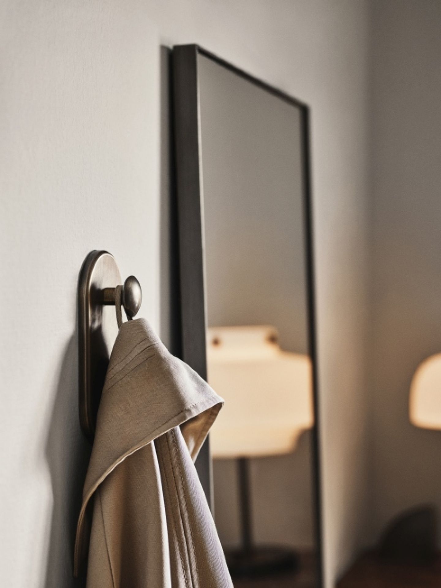 AndTradition Amore Spiegel, 190cm hoch, mit Handtuch an einem Haken im Vordergrund. Wandspiegel für Schlafzimmer und Bad.