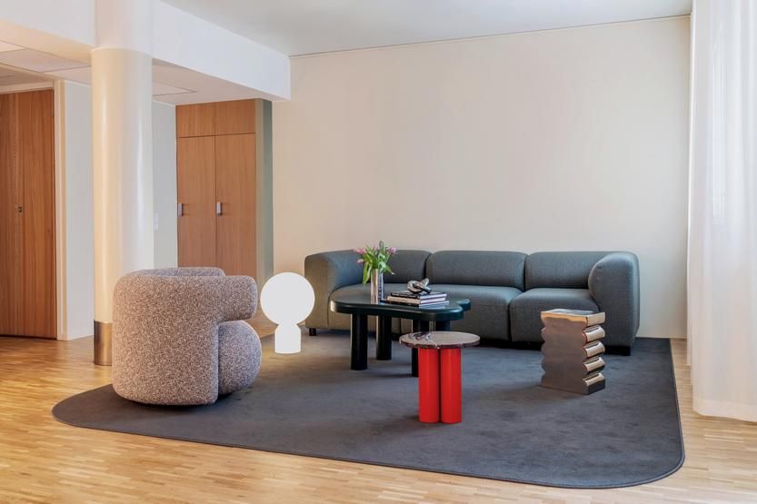 Wohnzimmer mit grauem Sofa, Teppich und mehreren Beistelltischen, darunter ein Dit Coffee Table von Normann Copenhagen.