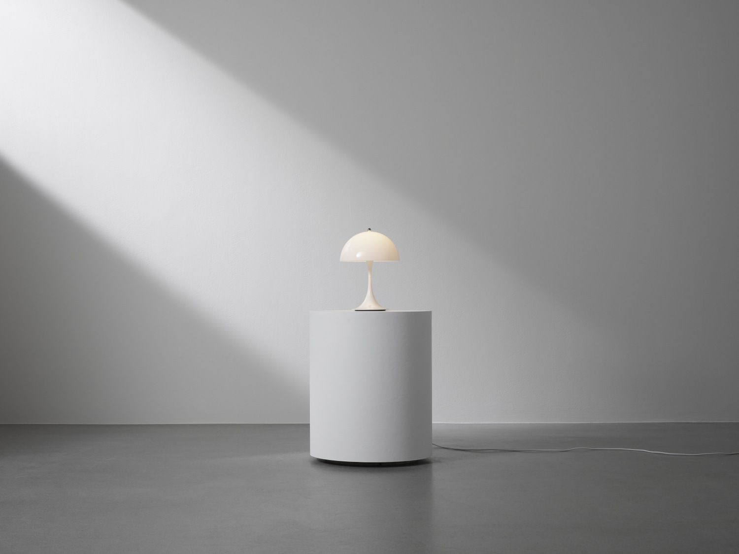 Panthella 250 Portable LED-Tischleuchte von Louis Poulsen in Opal auf weißem Sockel.